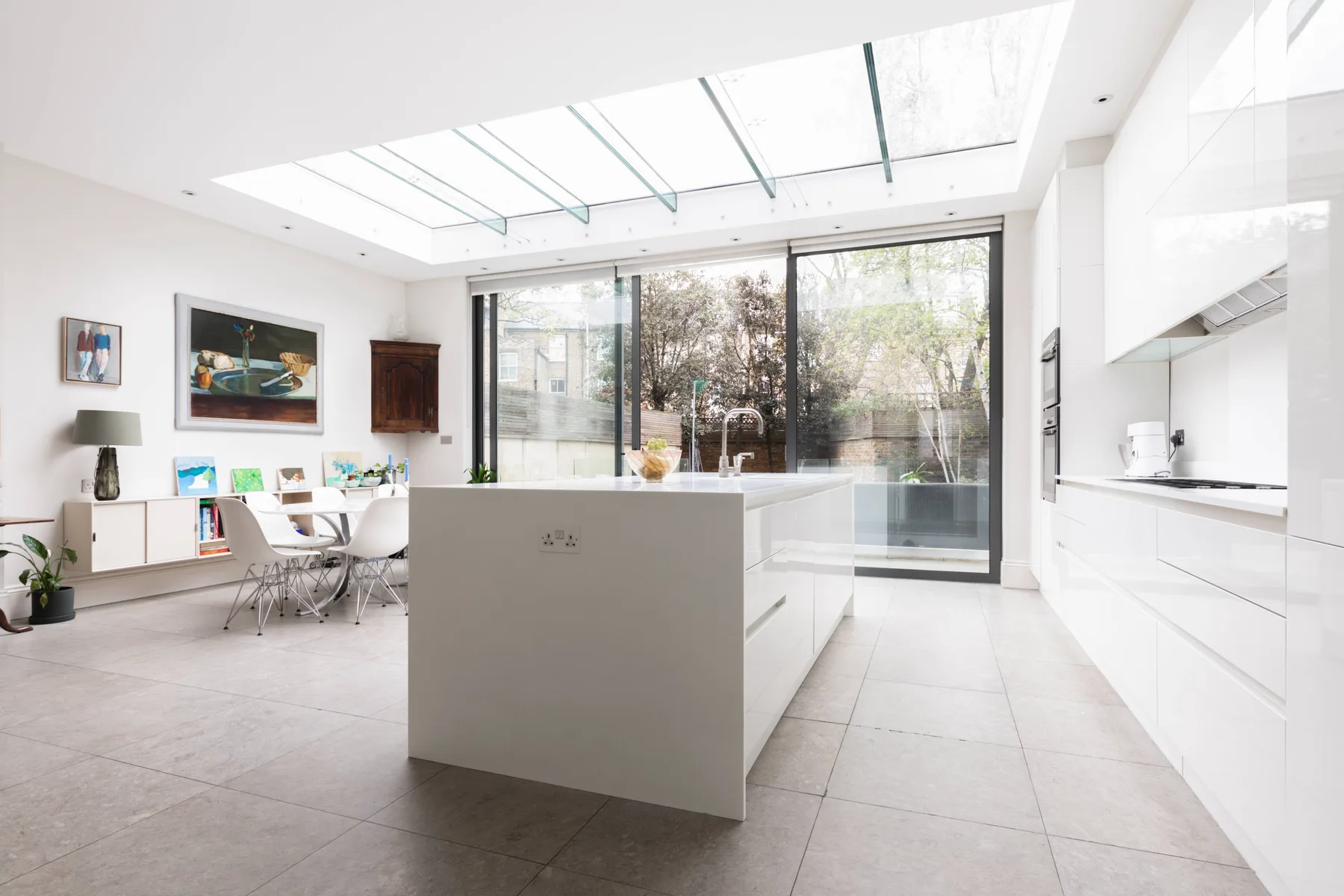 A bright modern kitchen with a central island and large windows.