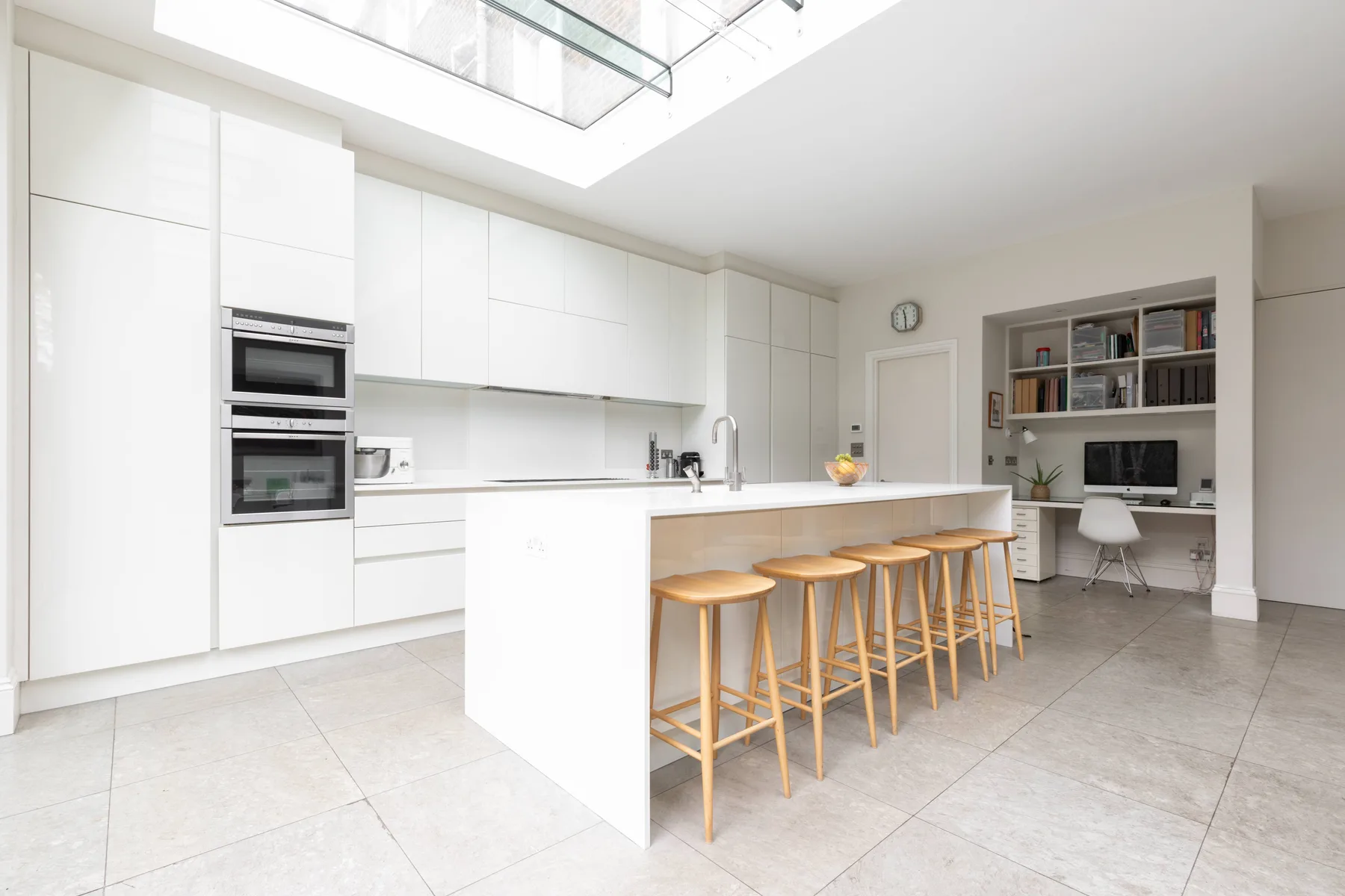 A bright modern kitchen with a large island and wooden stools.