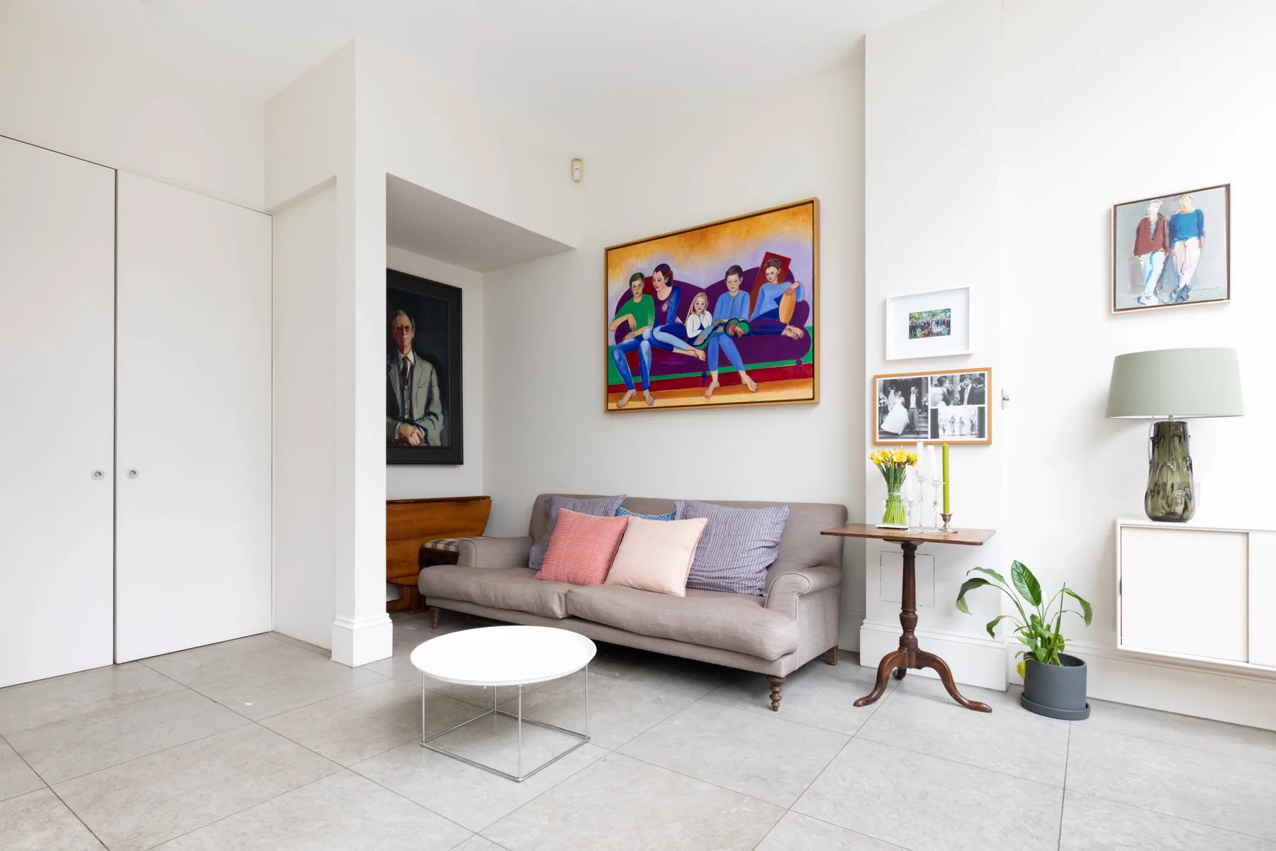 A bright living room with a sofa, framed artwork, and a small side table.