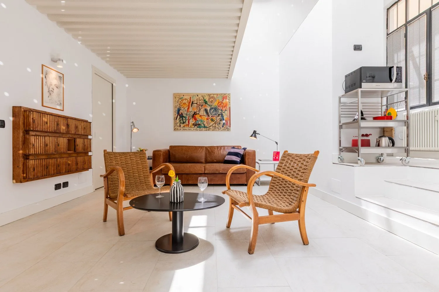 A bright living room with wicker seating arranged around a low black table.