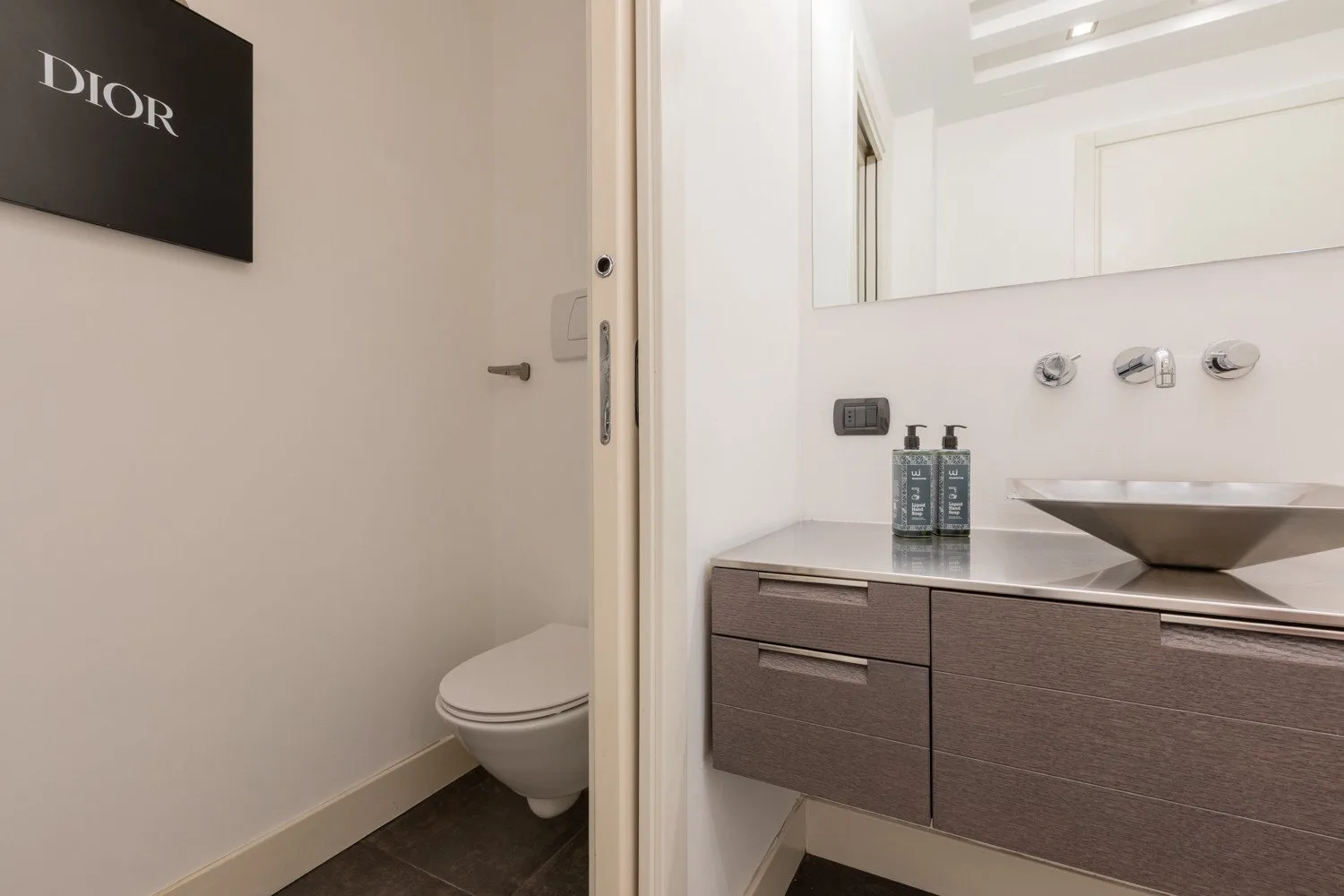 A bathroom with a sink vanity and a toilet beside the doorway.