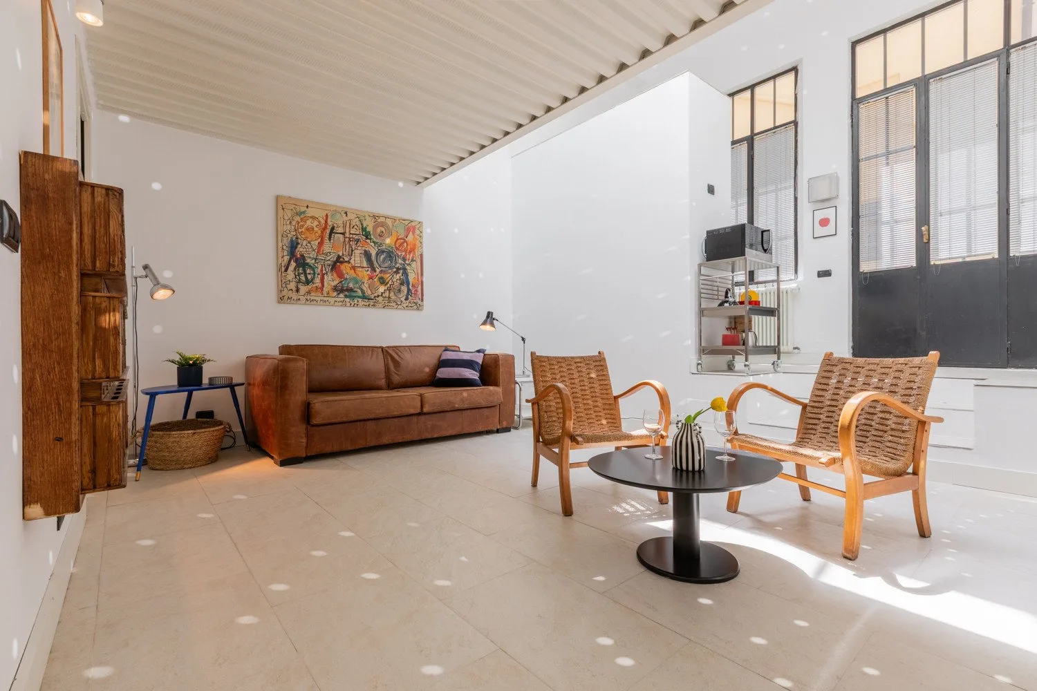 A bright living room with a brown sofa, wicker seating, and a low table.