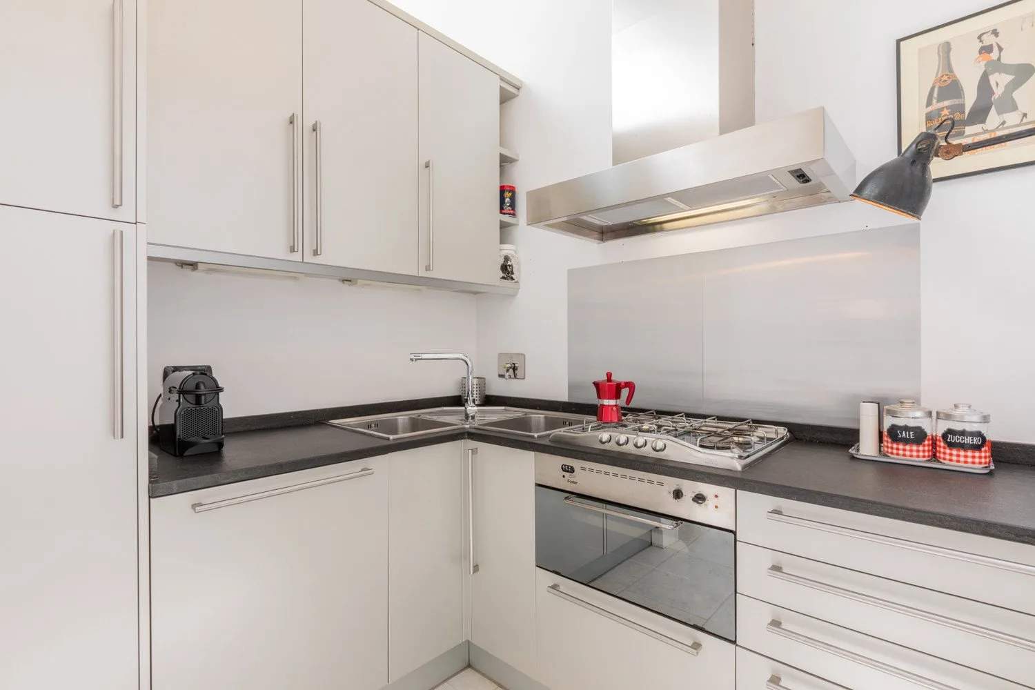 A bright kitchen with white cabinets and a countertop cooking area.