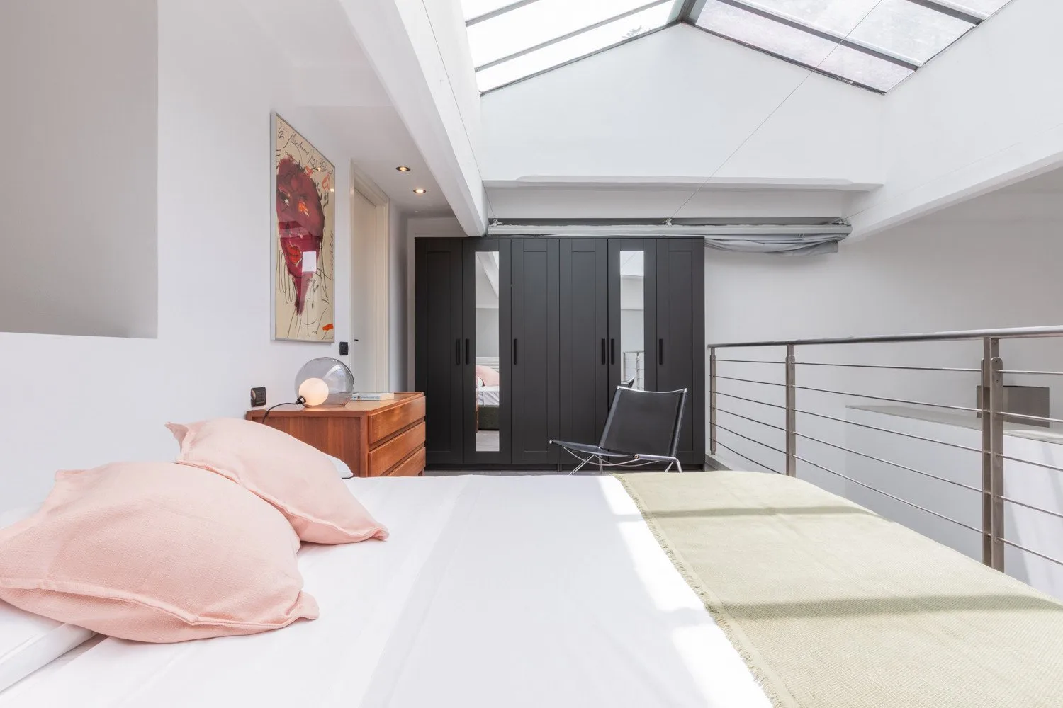 A bright loft bedroom with a bed beneath a skylight.