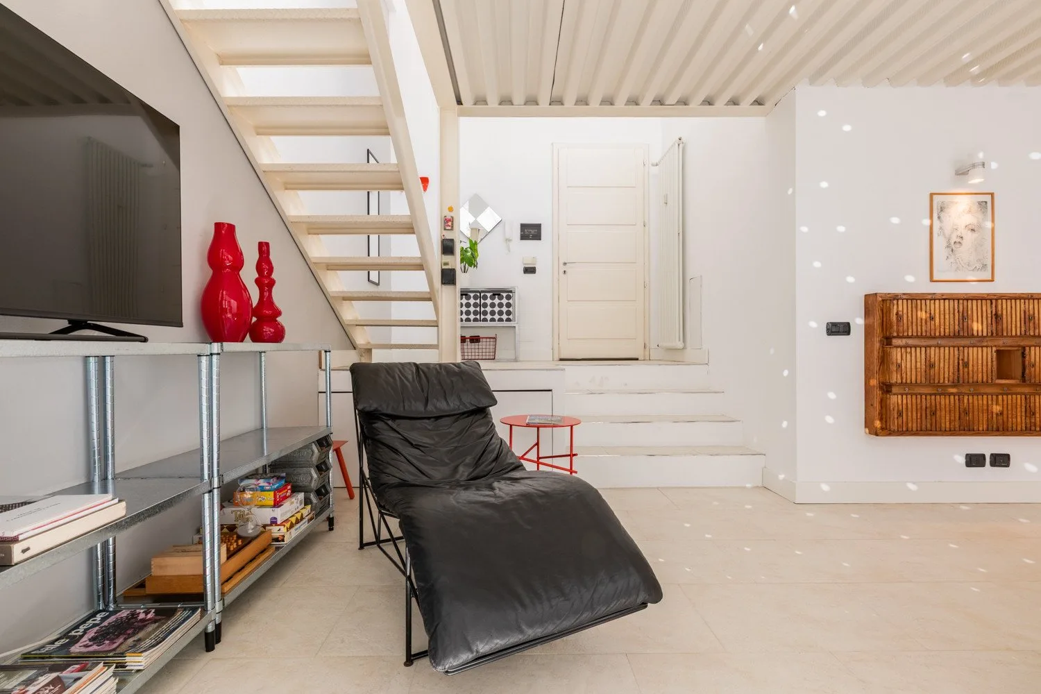 A bright living area with a black reclining lounge chair and a television on shelving.