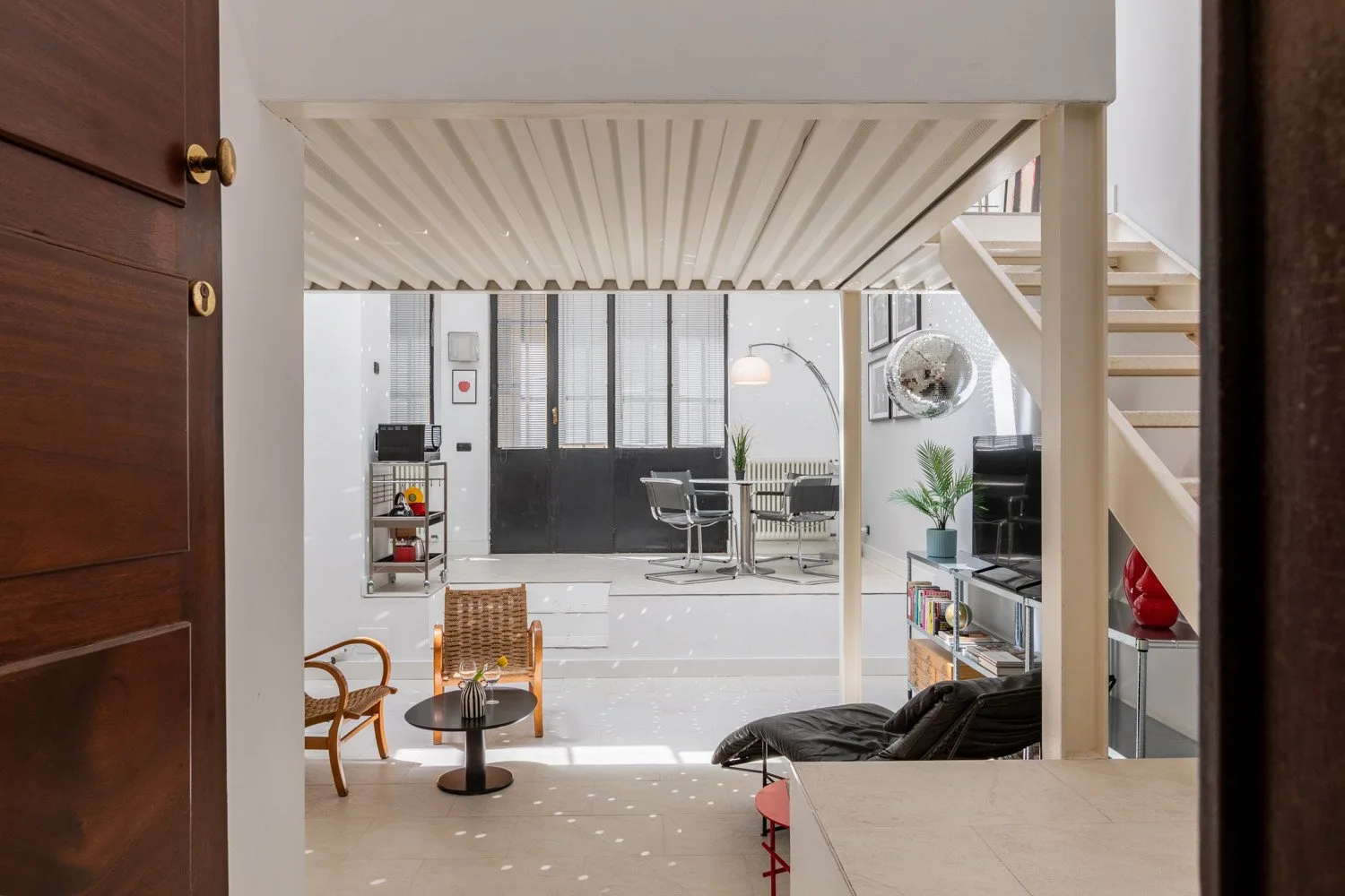 An open-plan living area with seating, a dining table, and a staircase.