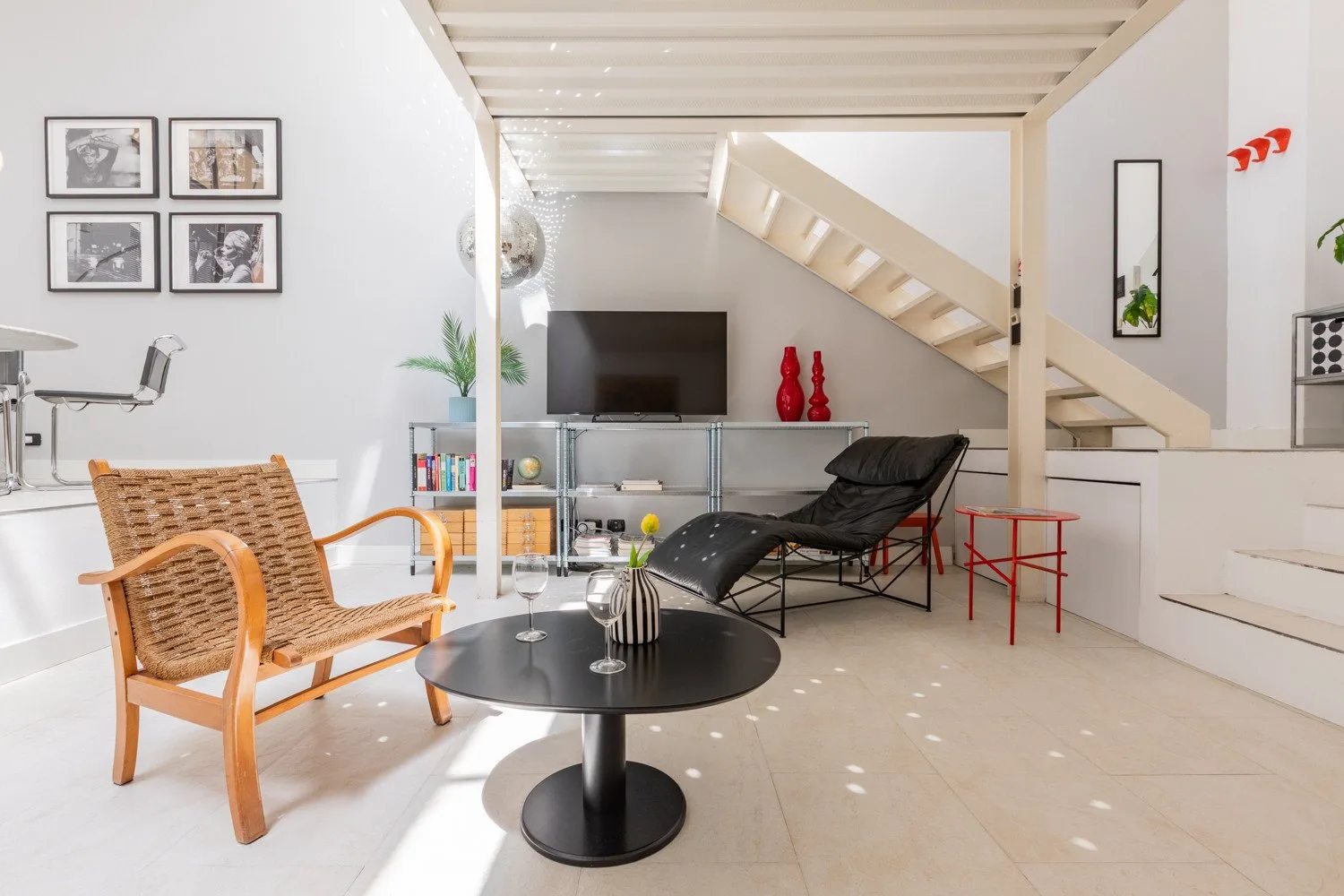 A bright living area with seating, a television, and stairs.