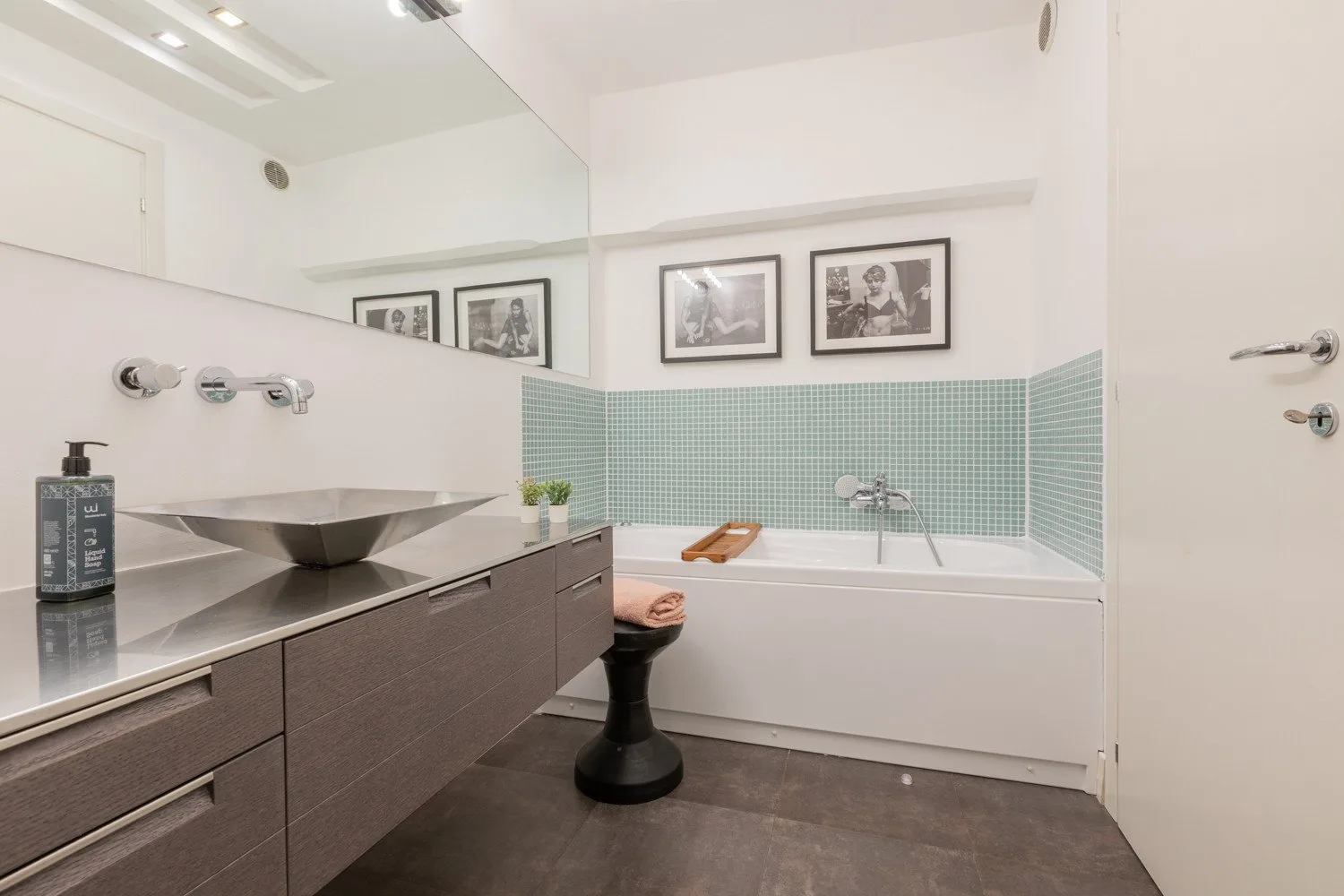 A bathroom with a bathtub, tiled walls, and a vanity with a basin.