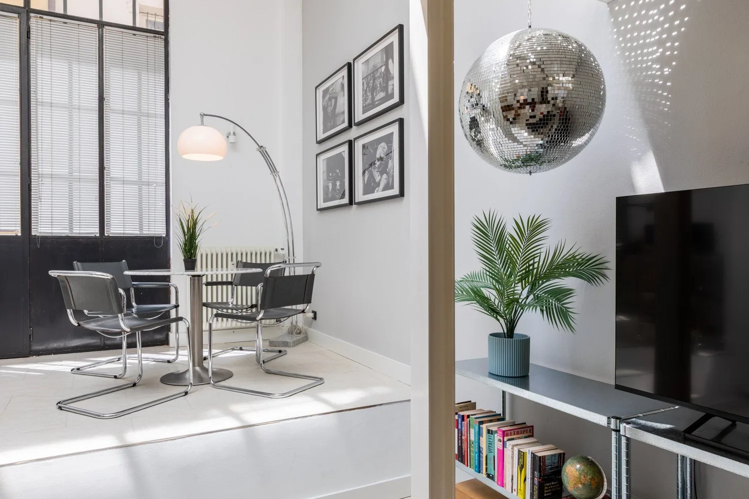 A bright seating area with framed artwork, a potted plant, and a television.