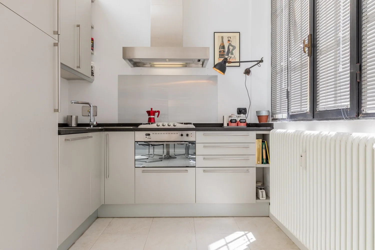 A bright modern kitchen with white cabinets and a countertop beneath the windows.
