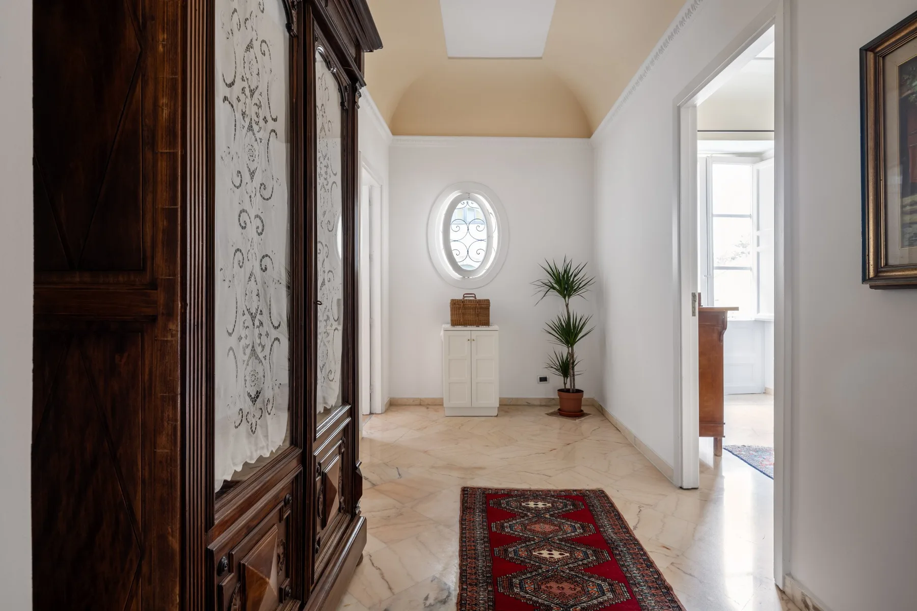 A bright hallway with a patterned runner and a round window.