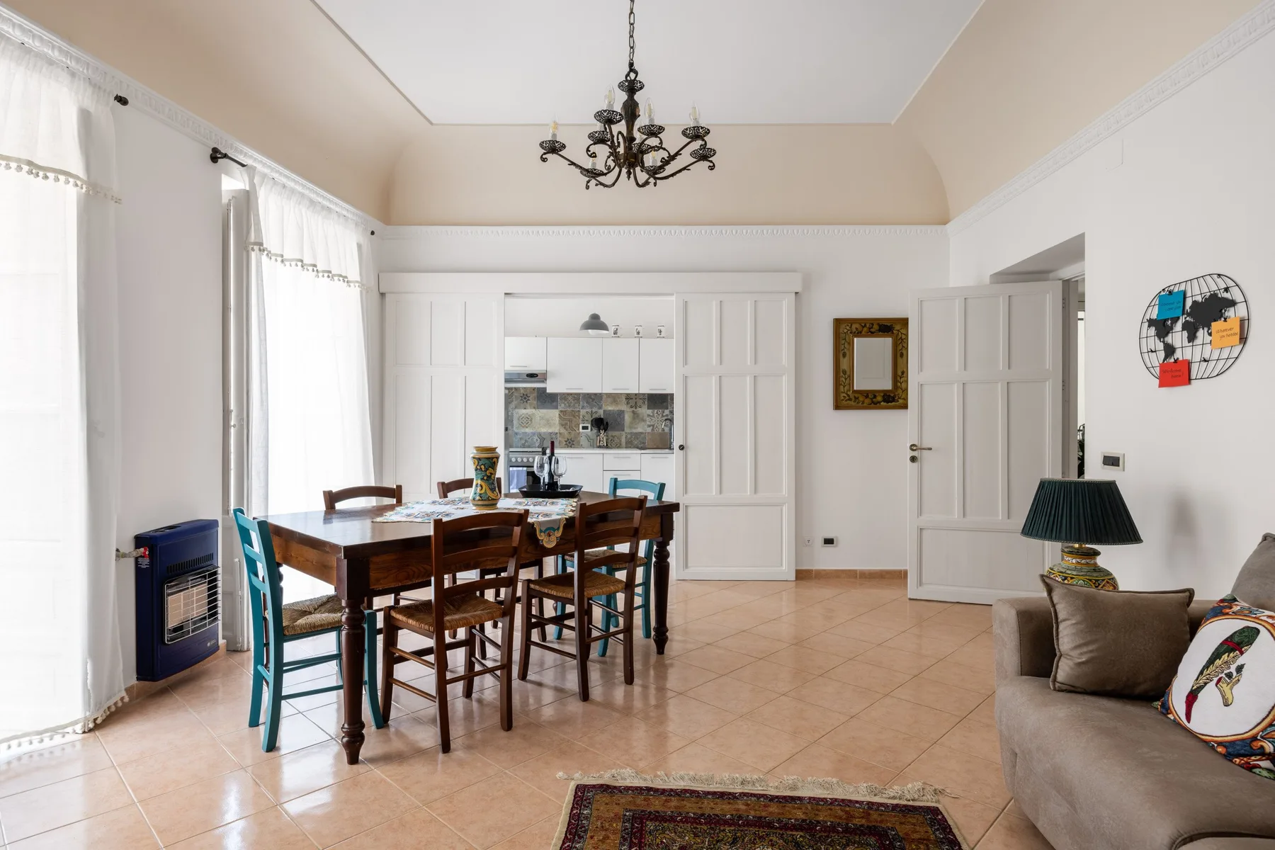 A bright dining area with a wooden table and seating beside tall windows.