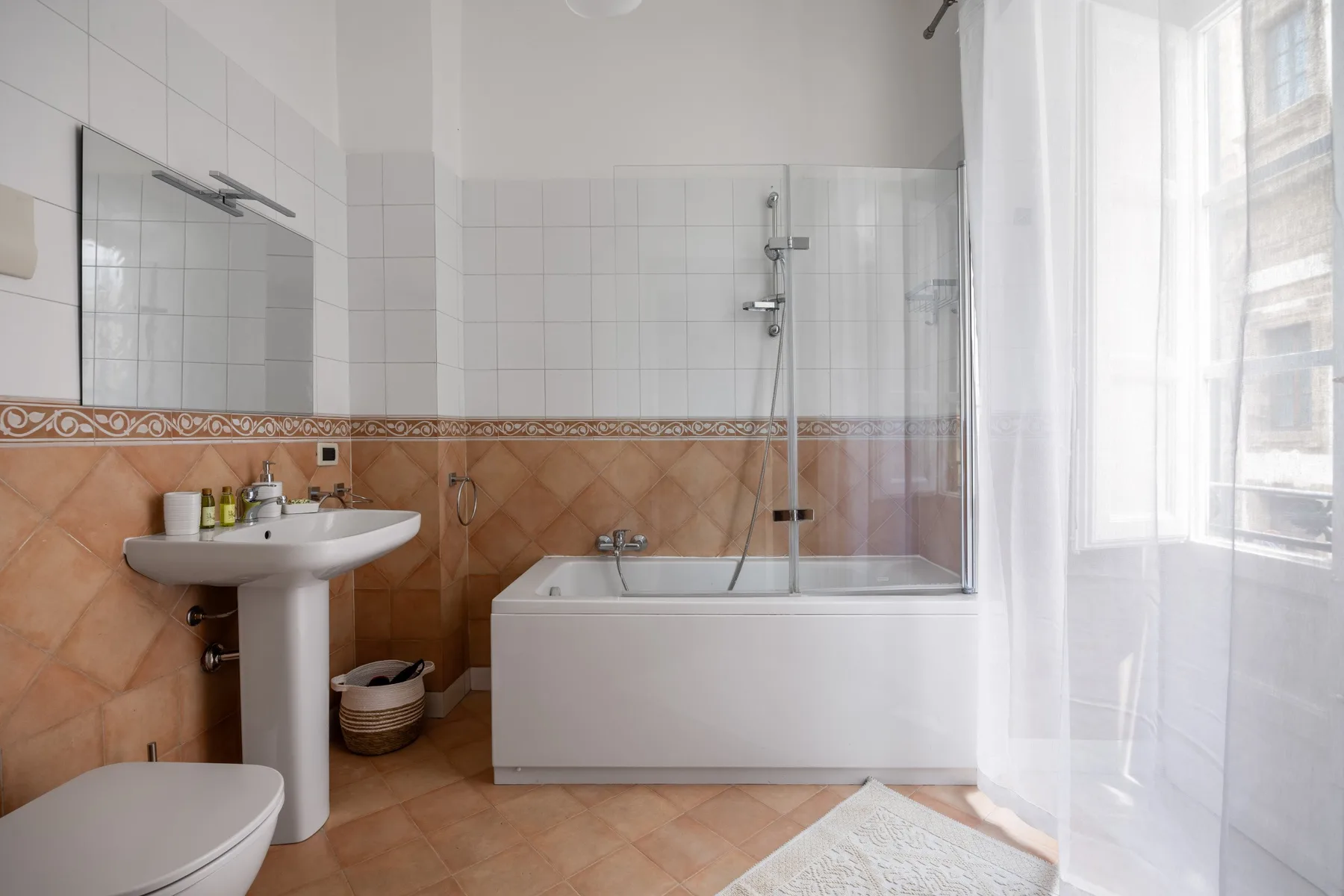 A tiled bathroom with a bathtub, shower, and pedestal sink.