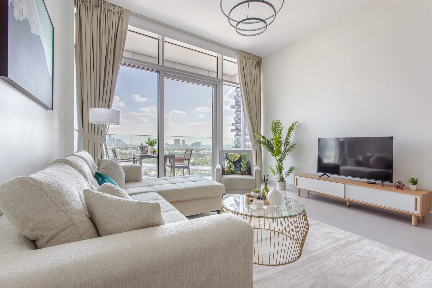 A bright living room with a seating area, television, and large windows.