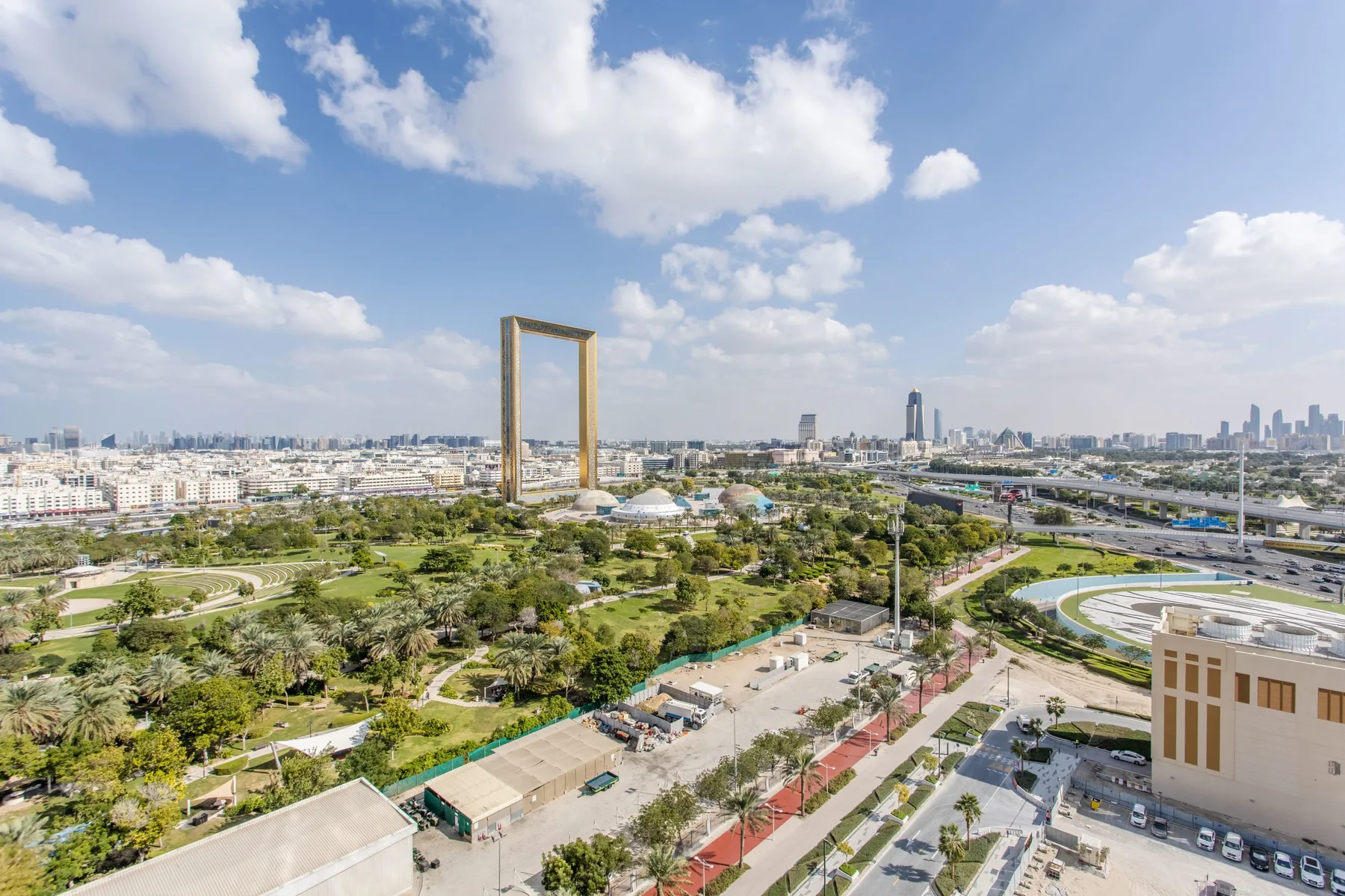 A city skyline and green parkland stretch beneath a partly cloudy sky.