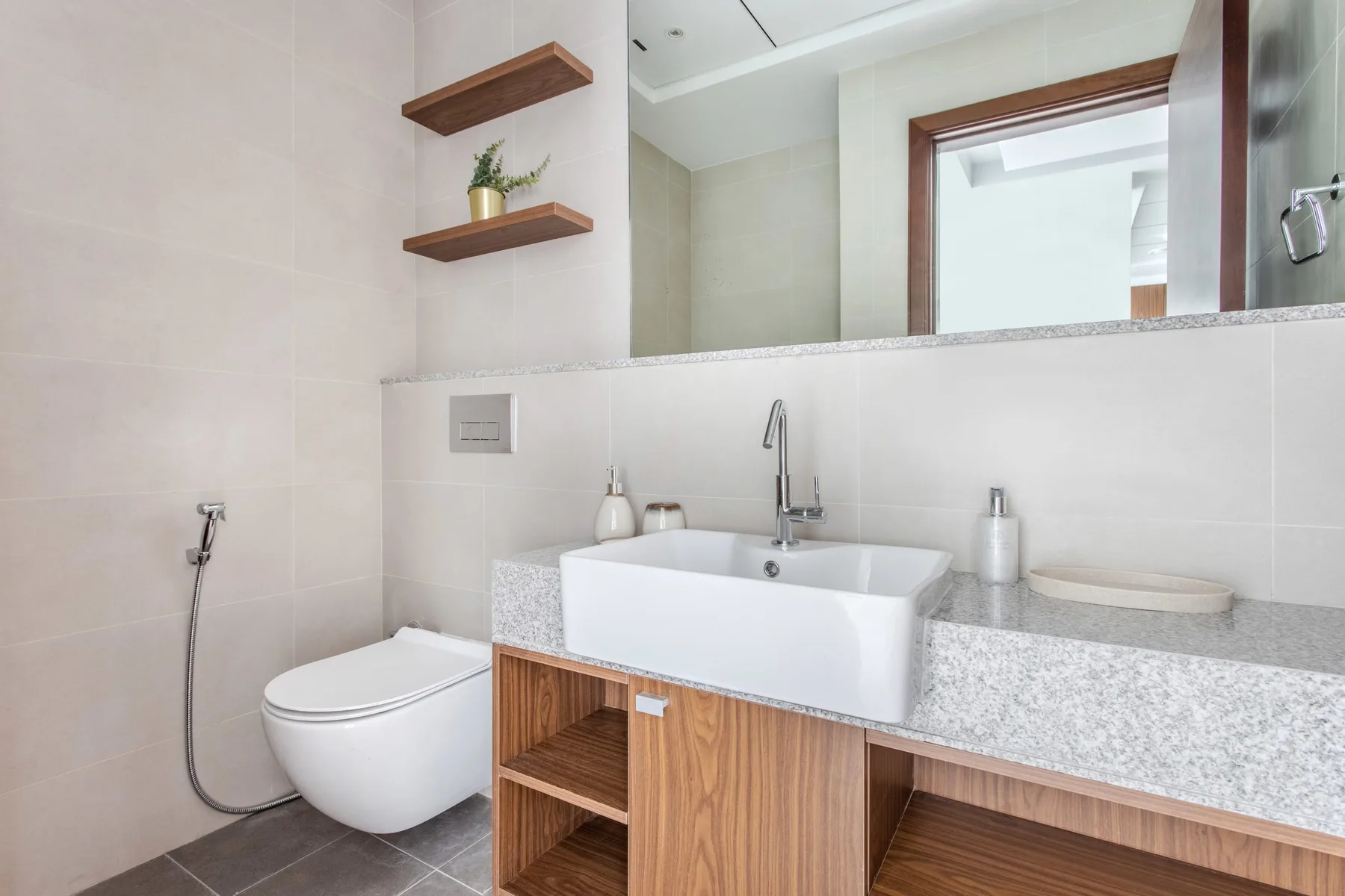 Un baño luminoso con lavabo, inodoro y un gran espejo de pared.