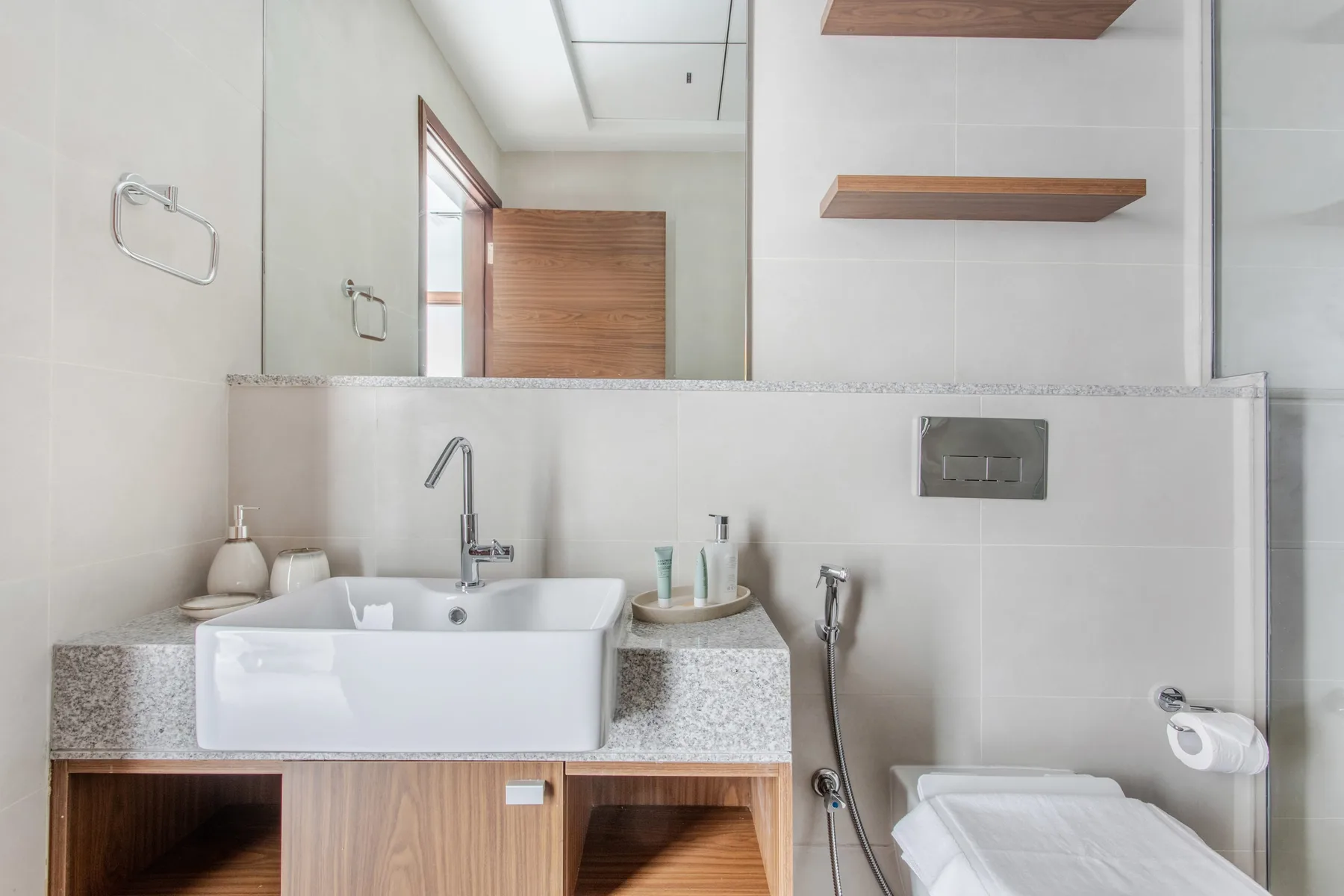 Un baño luminoso con lavabo, espejo de pared y zona de ducha.