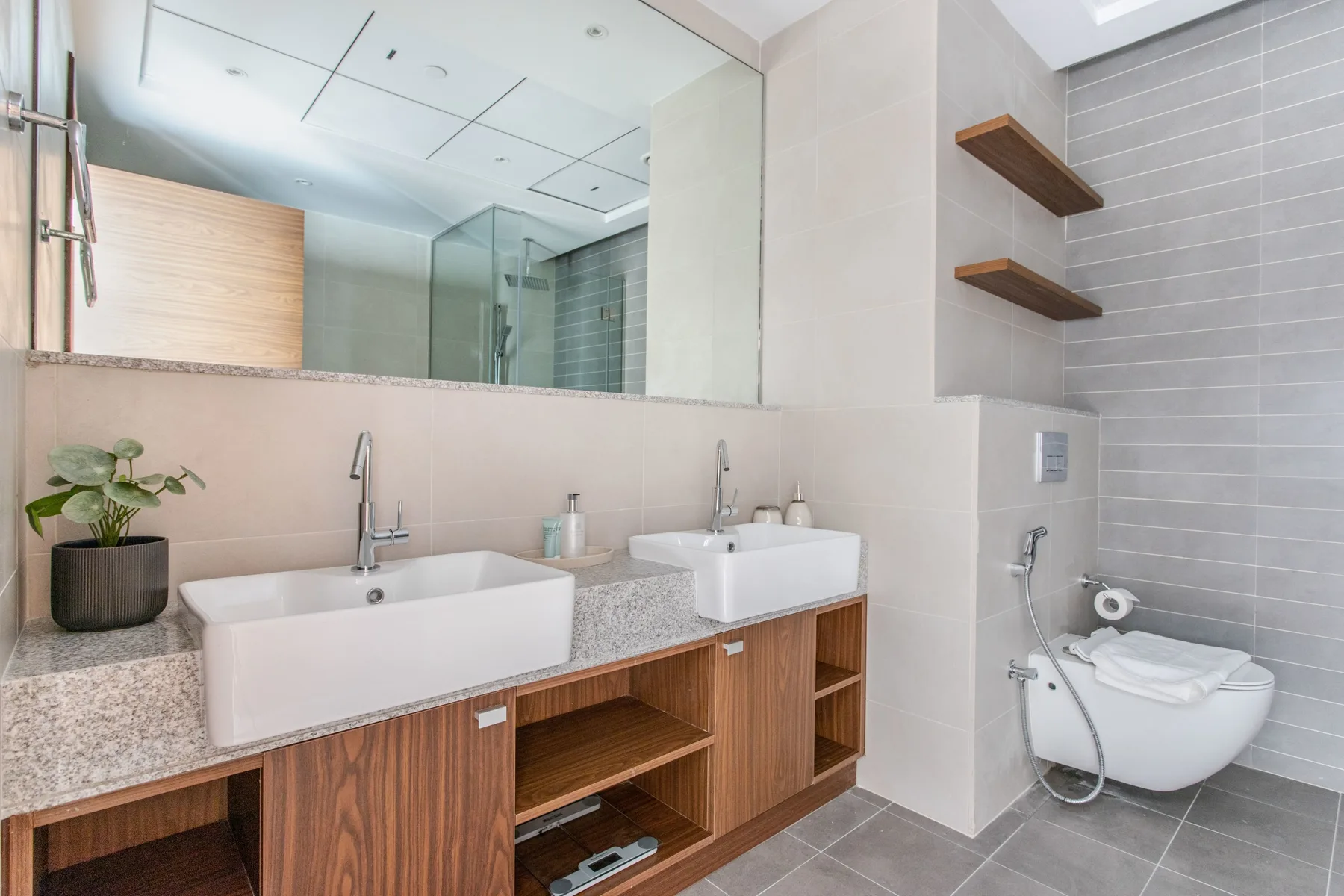 Un baño moderno con dos lavabos, un espejo grande y una ducha.
