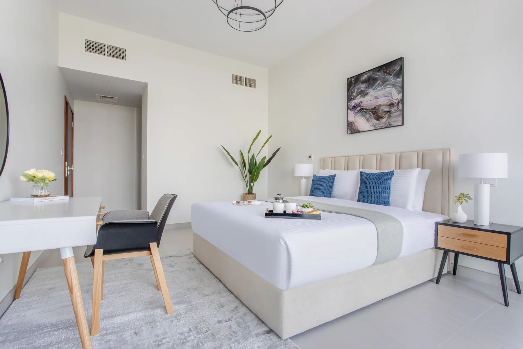 Un dormitorio luminoso presenta una cama bien arreglada con cojines azules.