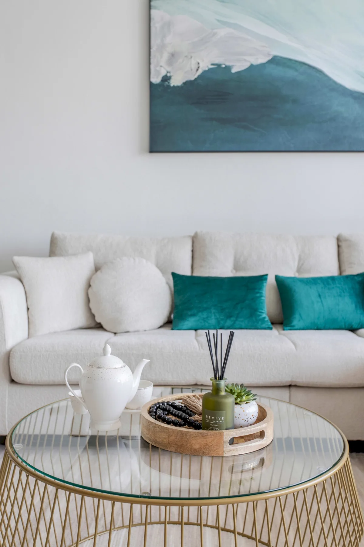 A living room seating area with a cream sofa and teal cushions.
