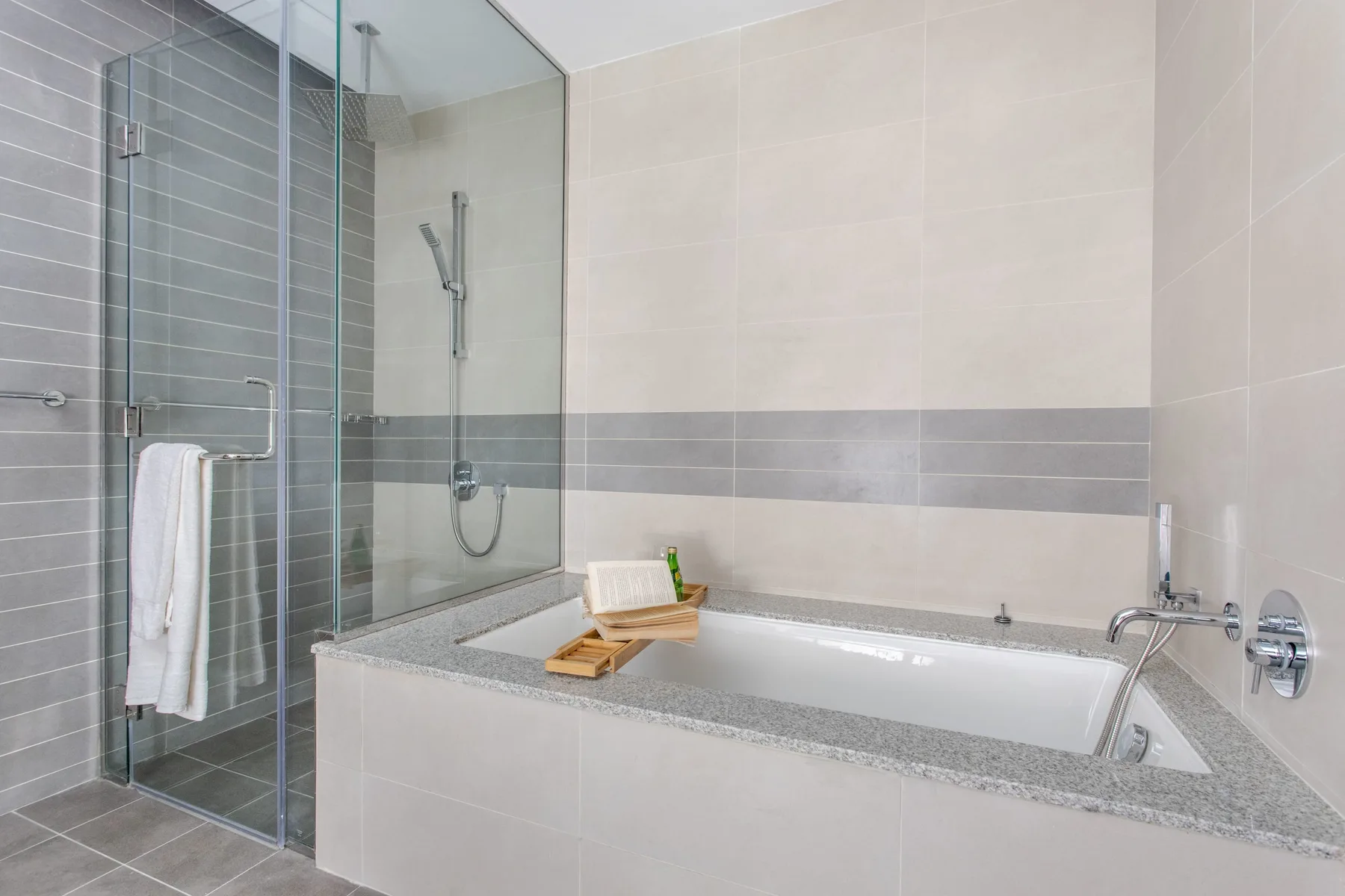 Un baño alicatado con bañera, mampara de ducha de vidrio y toallero.