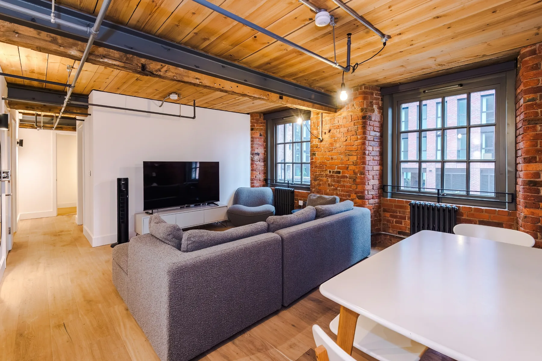 Living room with seating, a television, and large windows.