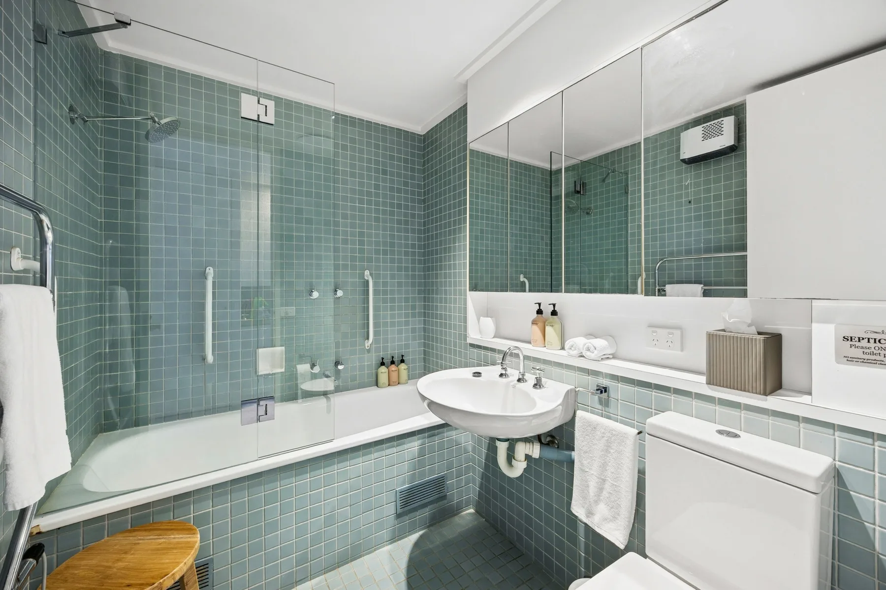 A tiled bathroom with a bathtub, sink, and mirrored wall.