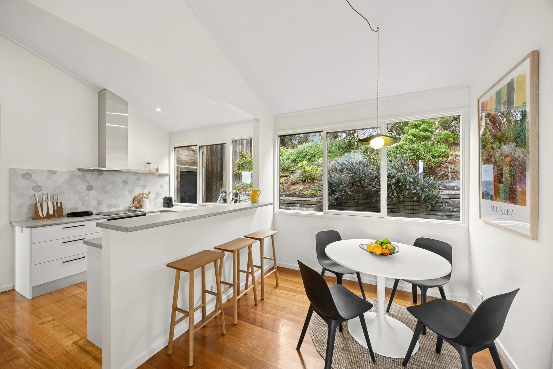 A bright kitchen and dining area with a counter and table beside large windows.