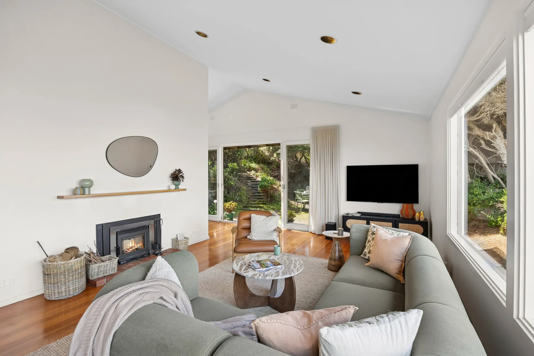 Bright living room with a fireplace, large windows, and garden views.