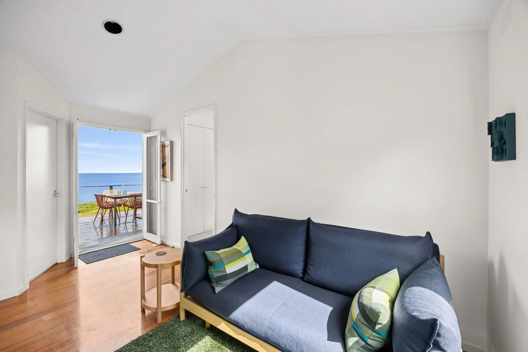 A bright living room with blue seating and an open door to a balcony.