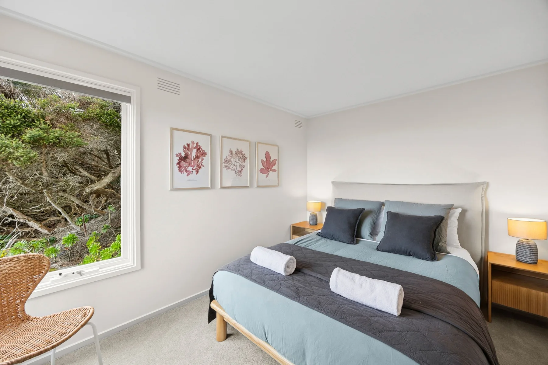 A bedroom with a bed dressed in blue and gray bedding beside a large window.