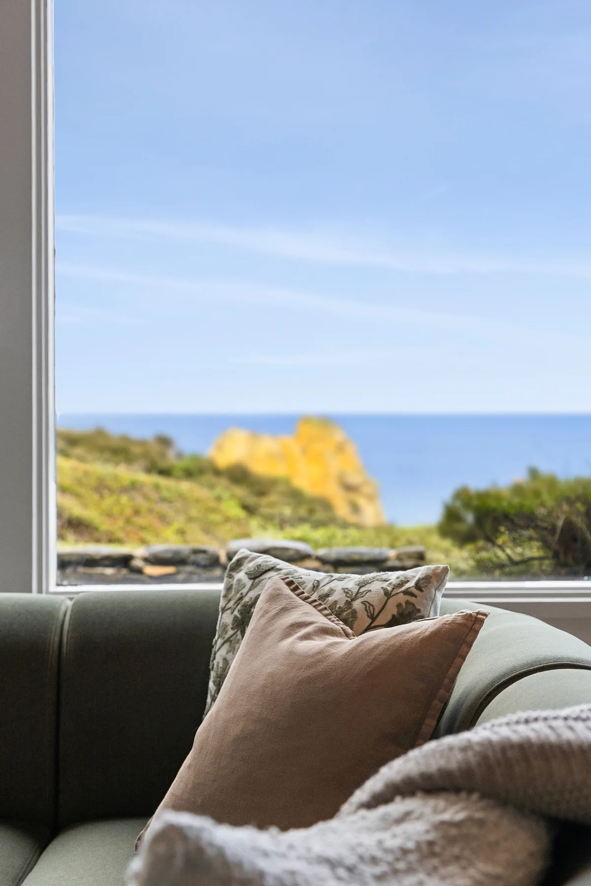 A living room seating area faces a large window overlooking the sea.