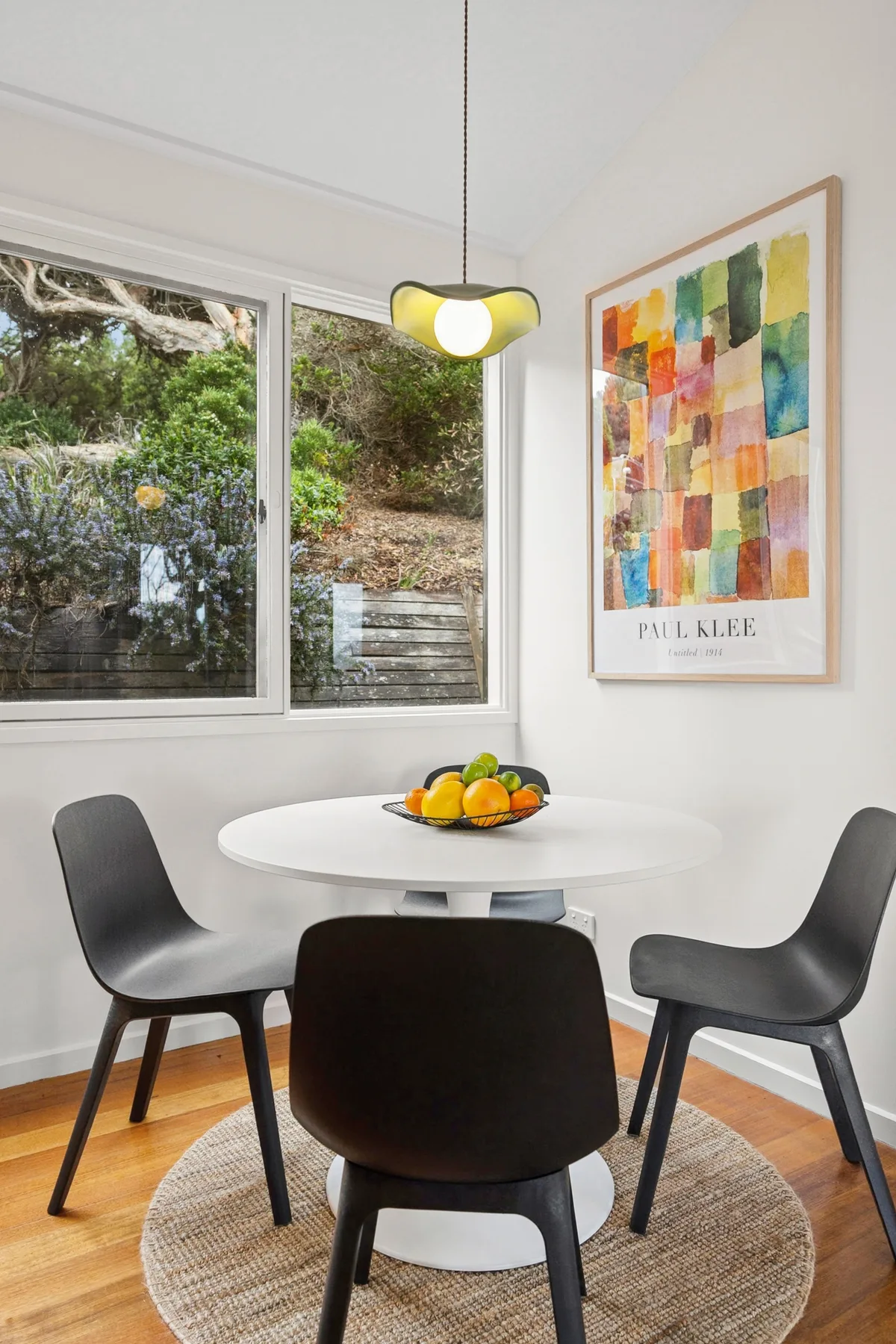 A bright dining area with a round table, chairs, and colorful wall art.