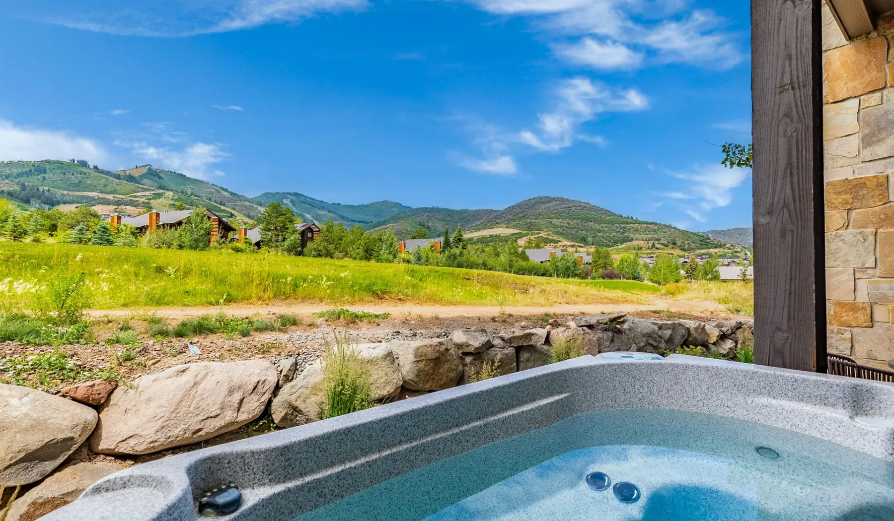 Una bañera de hidromasaje al aire libre mira hacia un valle verde y colinas lejanas.