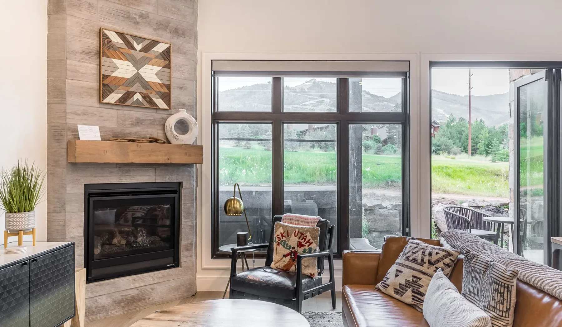 Sala de estar con chimenea, asientos y grandes ventanas con vistas a zonas verdes.