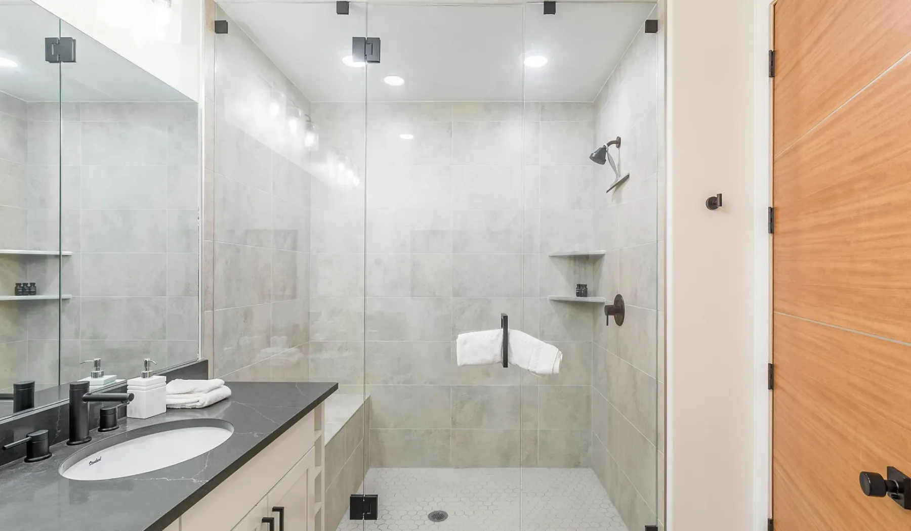 Un baño luminoso con una ducha de vidrio y un lavabo con mueble.