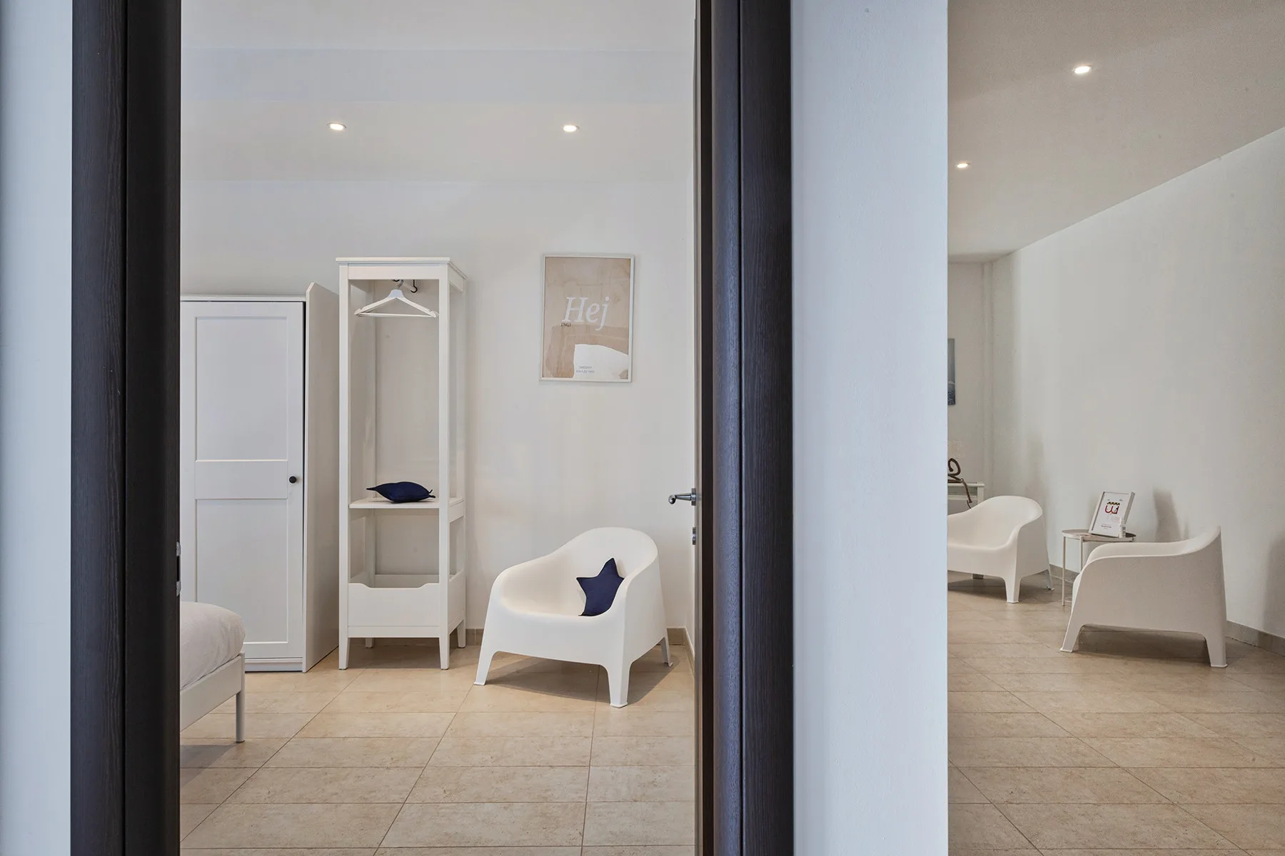 Una habitación luminosa con asientos blancos y un armario abierto alto.