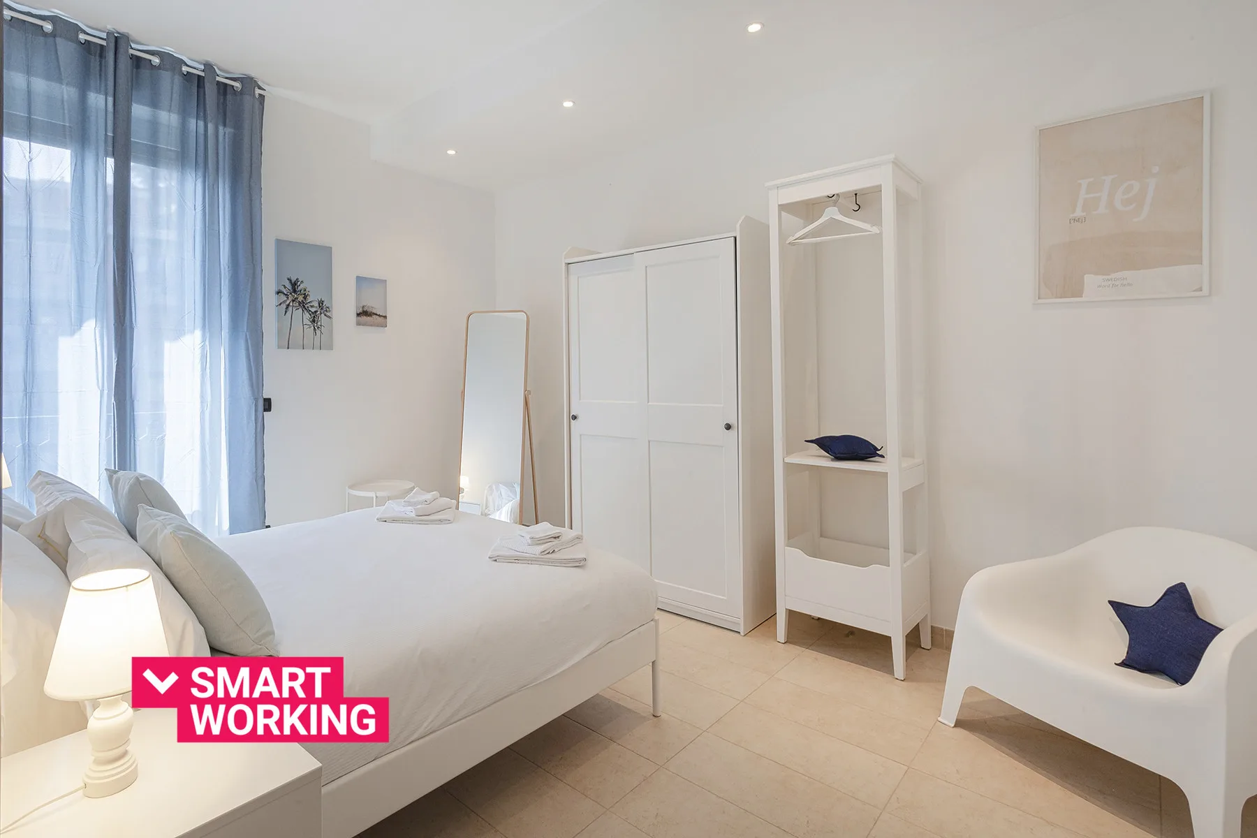 Un dormitorio luminoso con una cama, un armario y una pequeña zona de estar.