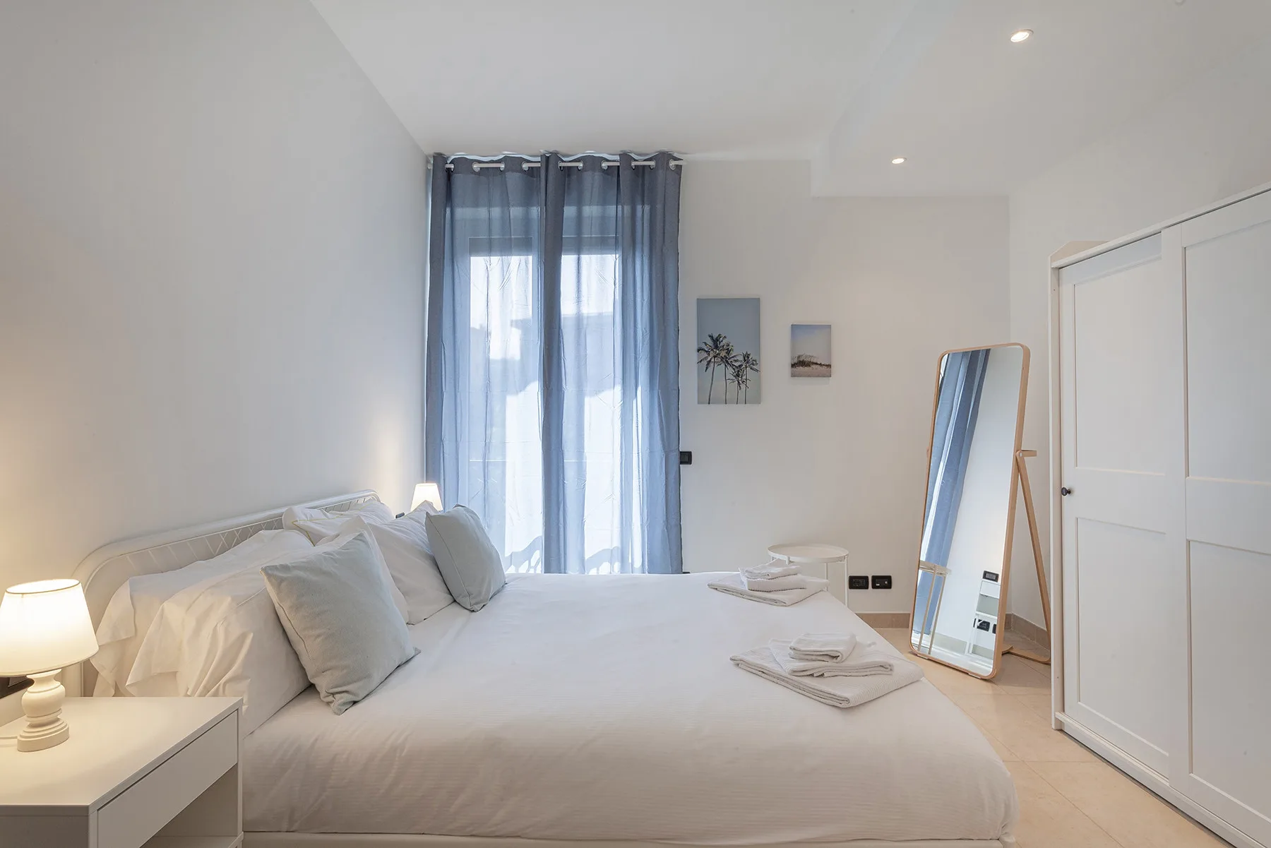 Un dormitorio luminoso con una cama bien tendida y cortinas azules.