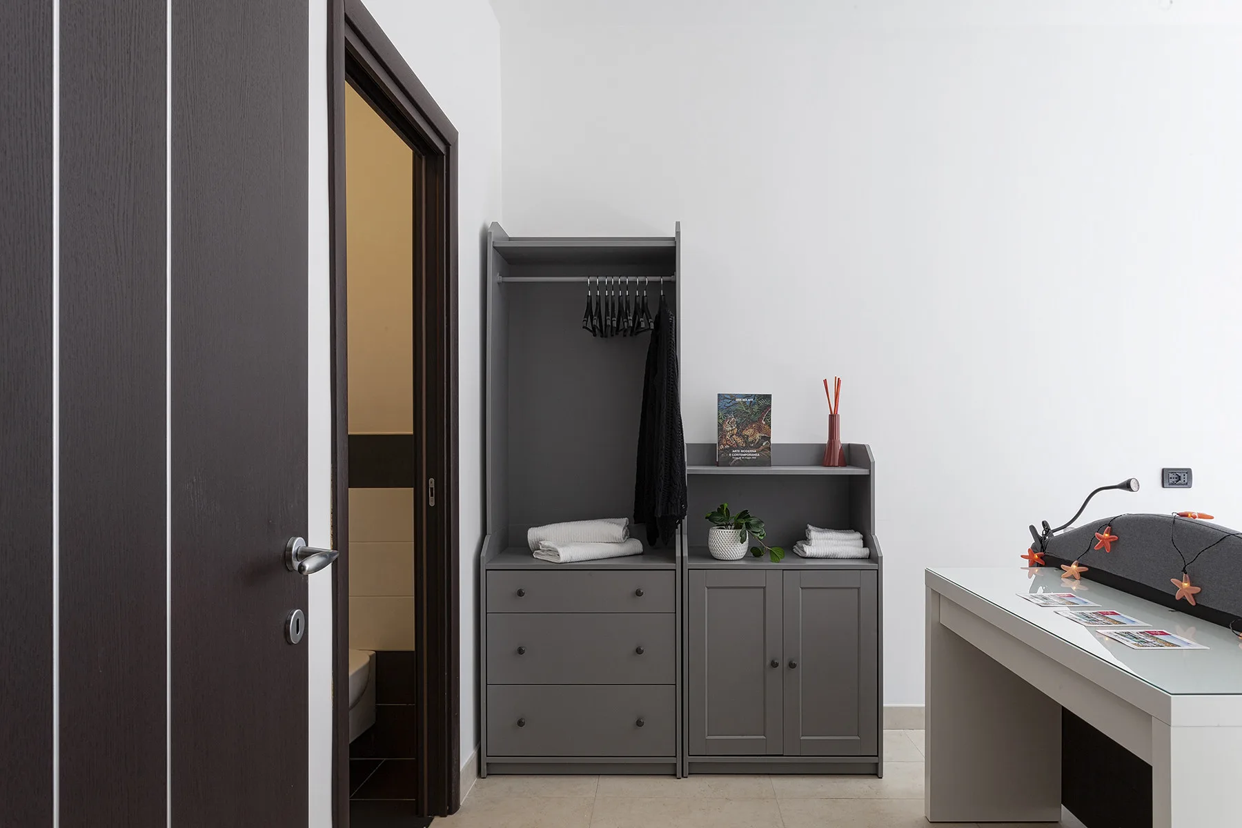 Un dormitorio con un armario oscuro y un escritorio junto a la pared.