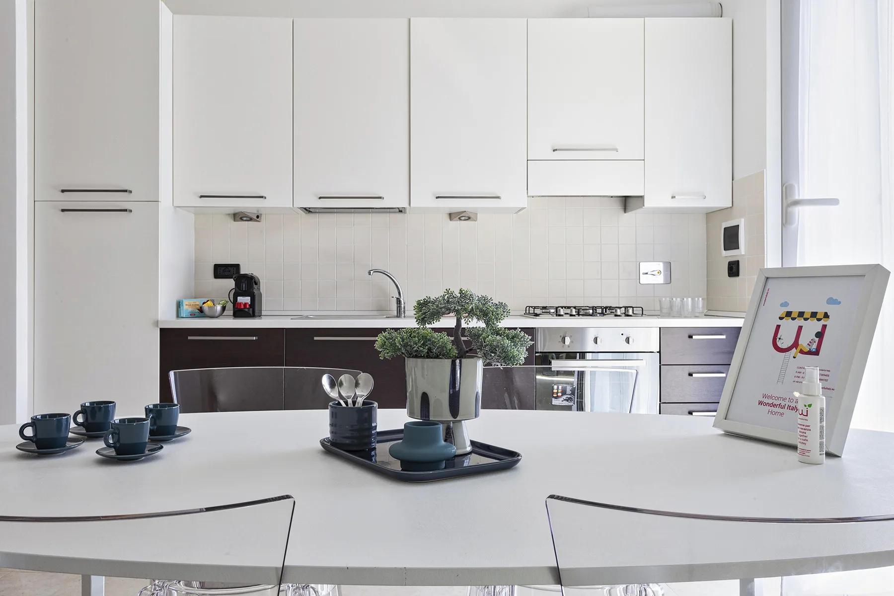 Una cocina moderna y luminosa con armarios blancos y una mesa de comedor en primer plano.