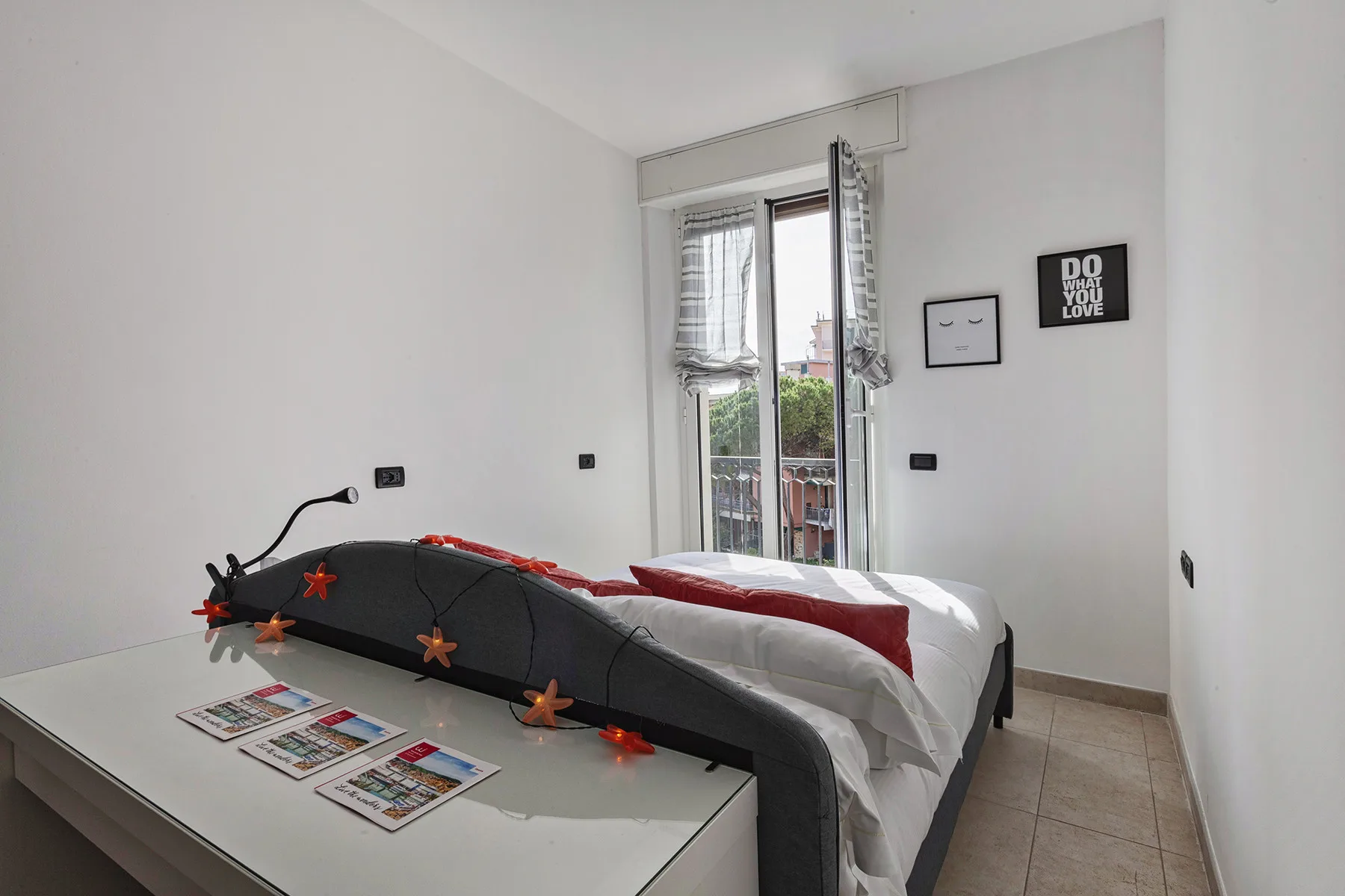 Un dormitorio con una cama junto a un escritorio y una ventana alta.