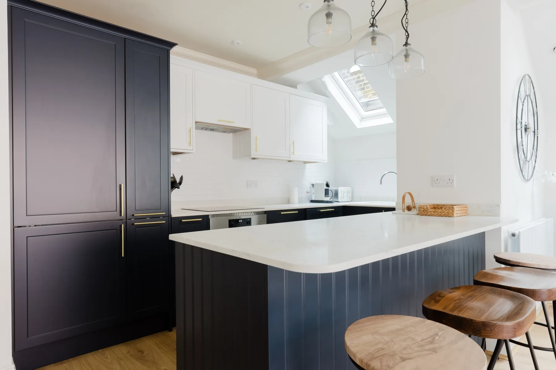A bright kitchen with a large island and wooden stools.