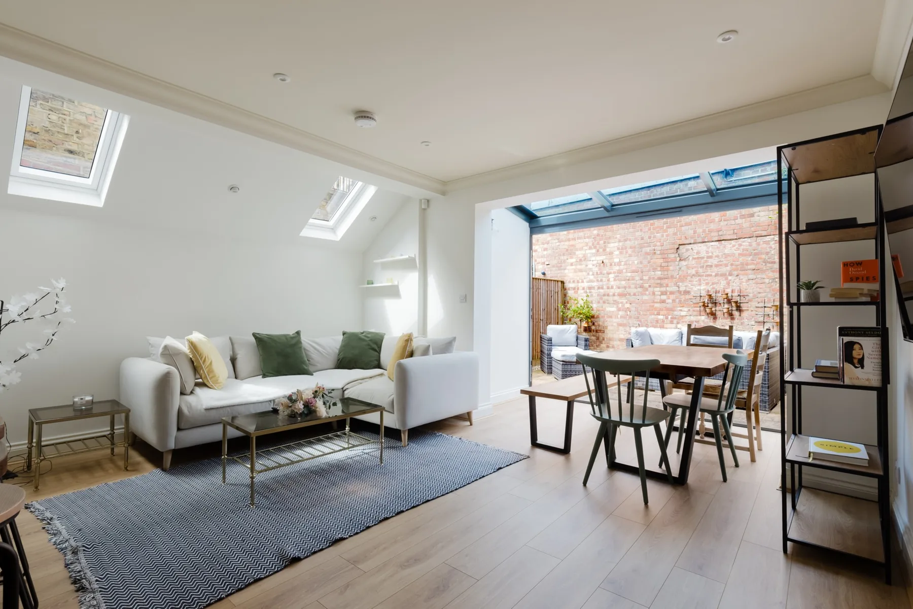 A bright living room with seating and a dining table beside a brick-walled patio.