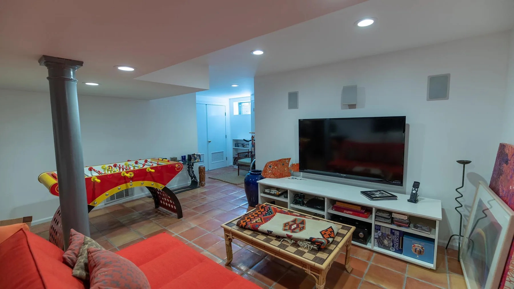 Una sala de estar con asientos rojos, un televisor y una mesa colorida.