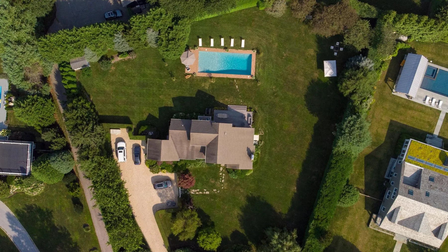 Una vista aérea muestra una casa, césped alrededor y una piscina.