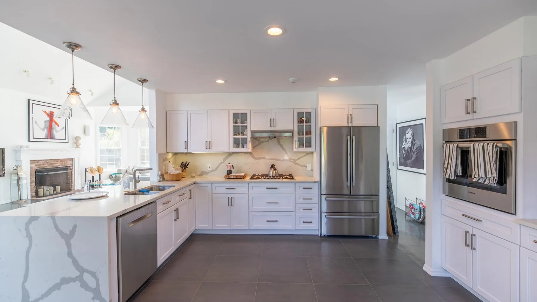 Una cocina luminosa con gabinetes blancos, una isla central y electrodomésticos de acero inoxidable.