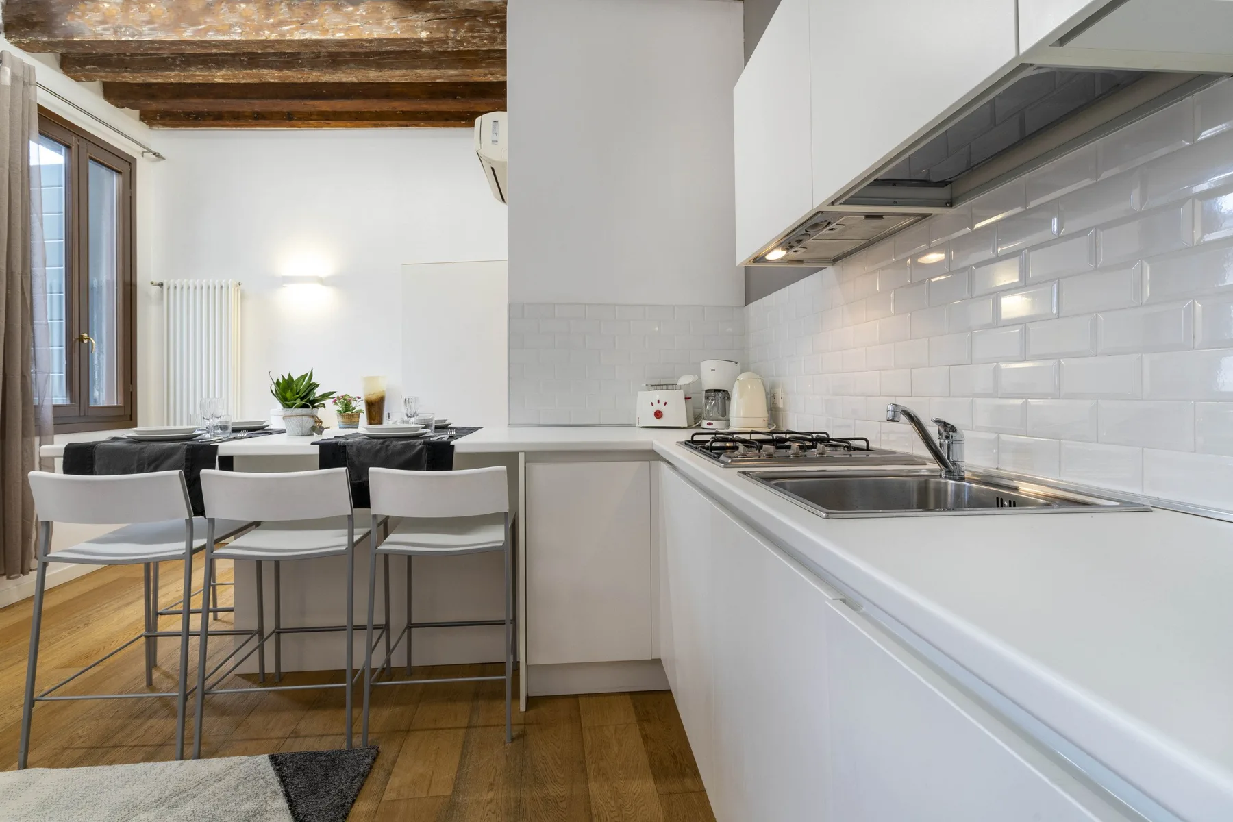 A bright kitchen with a long counter, sink, and dining table by the window.