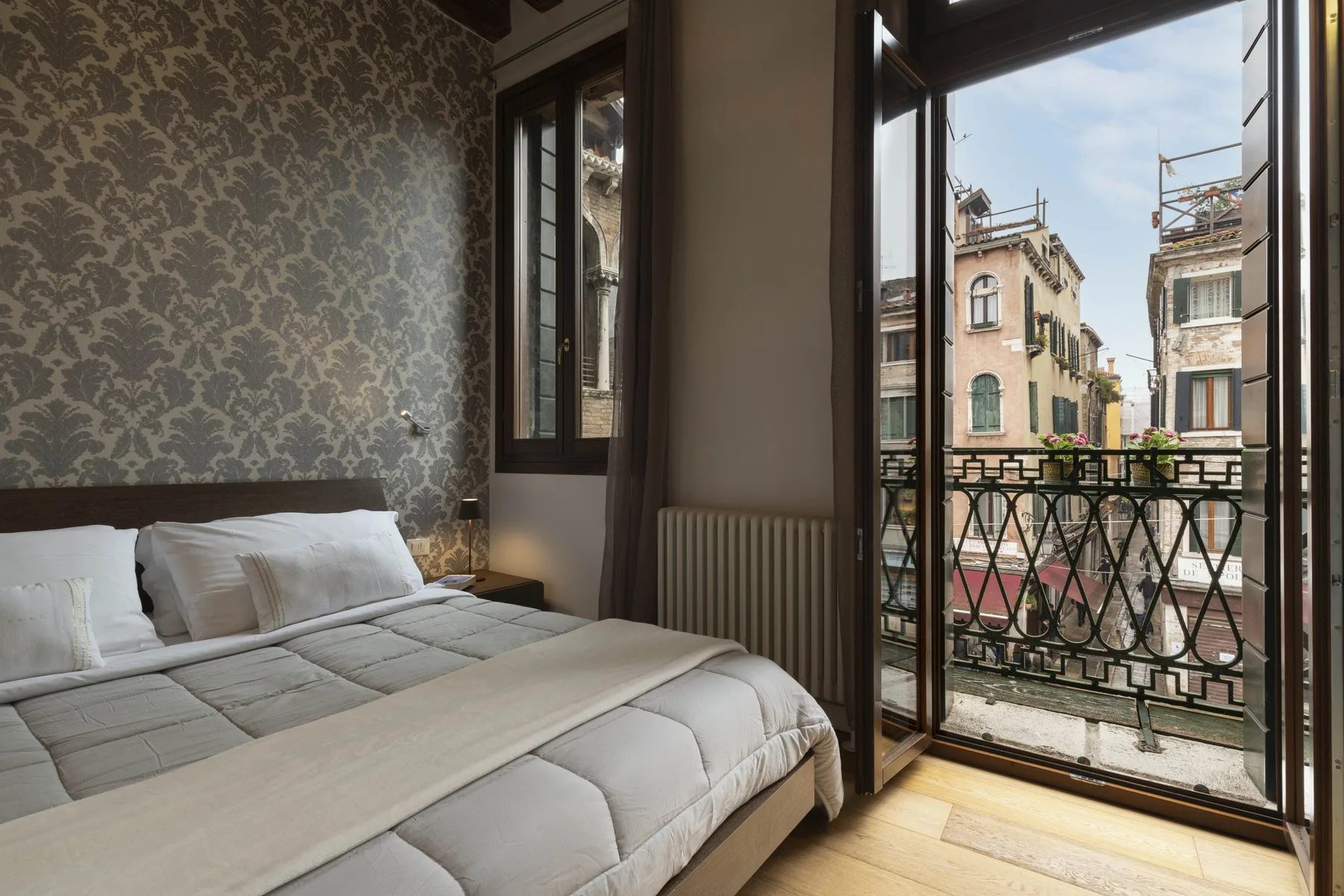 A bedroom with a neatly made bed beside an open balcony door.