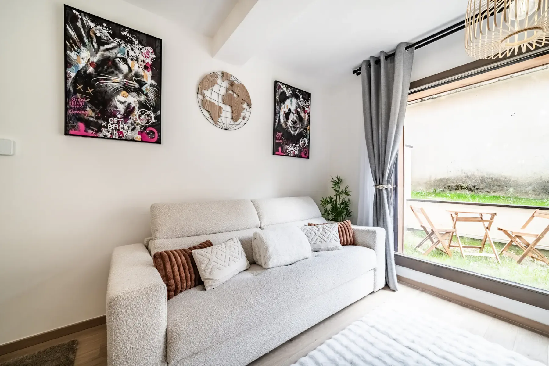 A bright living room with a light-colored sofa beside a large window opening onto a patio.